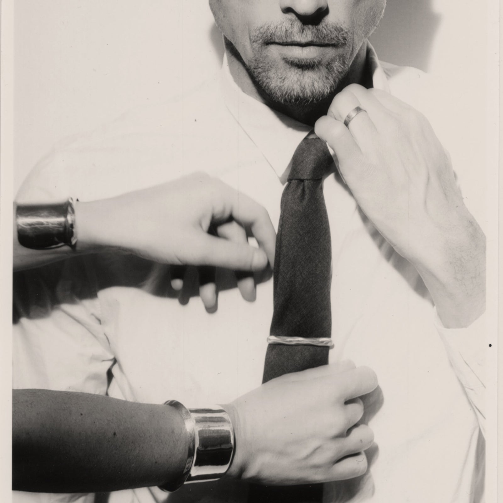 Models wearing AGMES .925 sterling silver Cliff Cuff and Astrid Tie Clip on black tie. Black and white image.