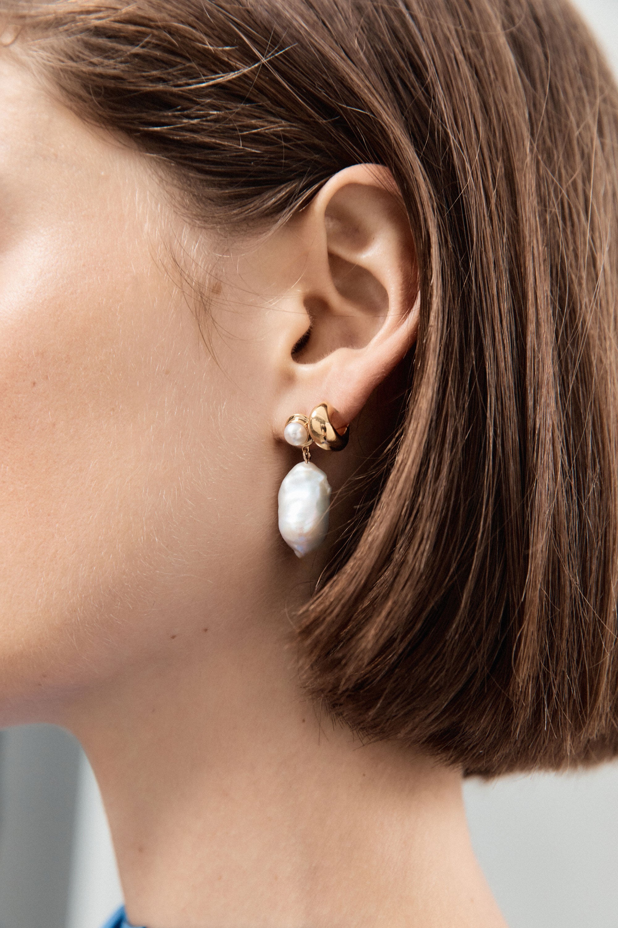 Woman wearing AGMES 18k gold vermeil thick hoop huggie earrings.