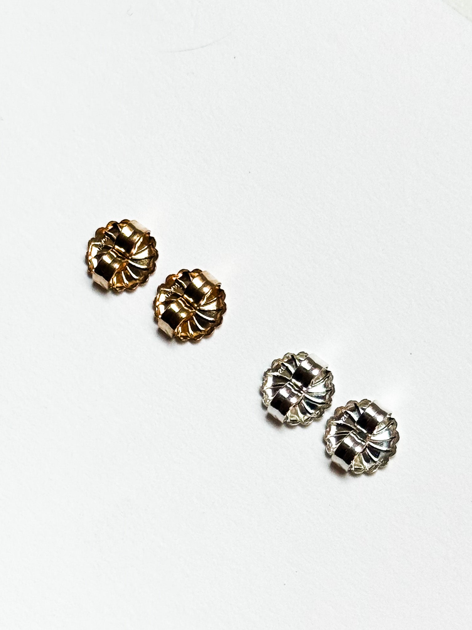 Four AGMES 18k gold vermeil and .925 sterling silver earring backs on white background.