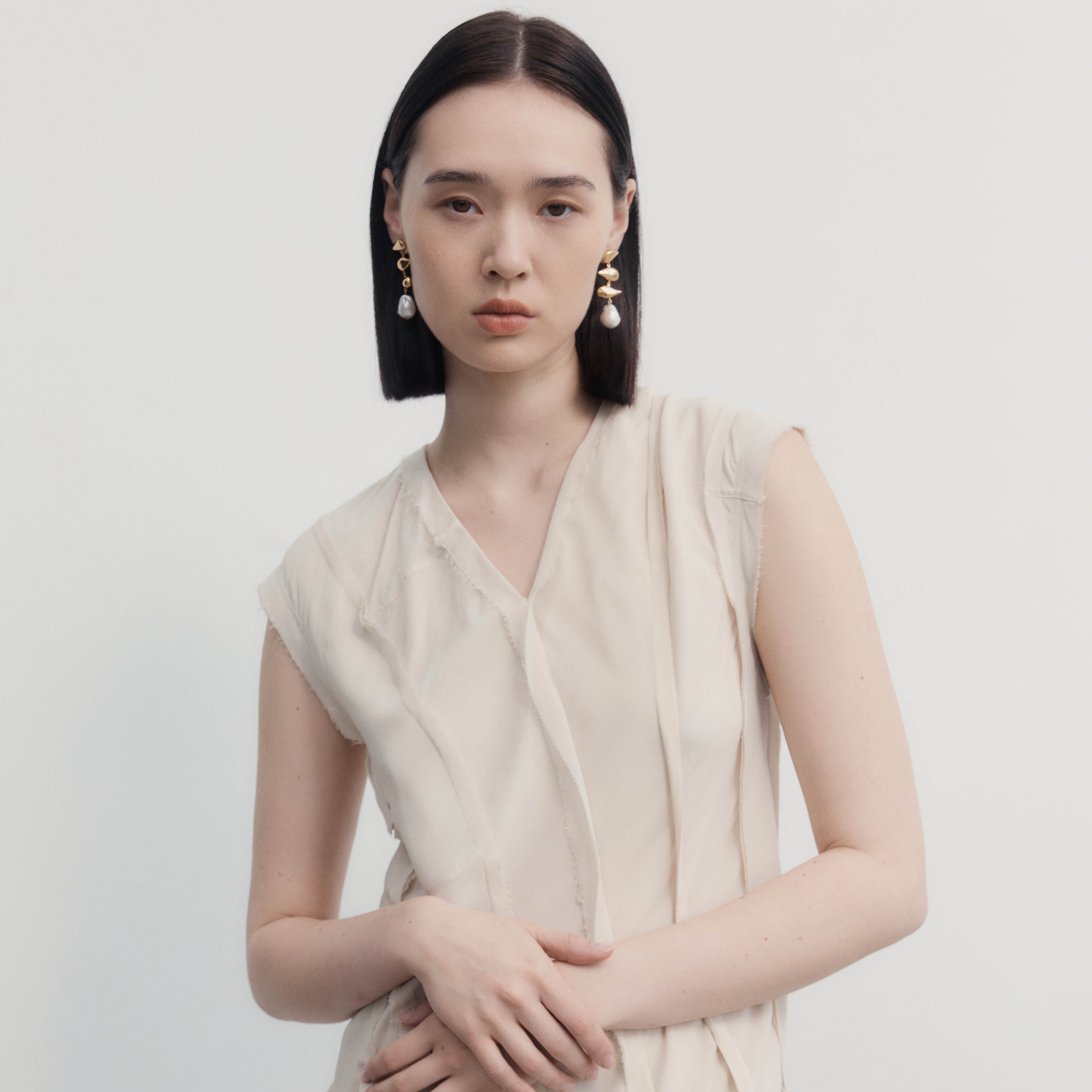 Woman wearing AGMES 0.925 sterling silver drop pearl Flora earrings.