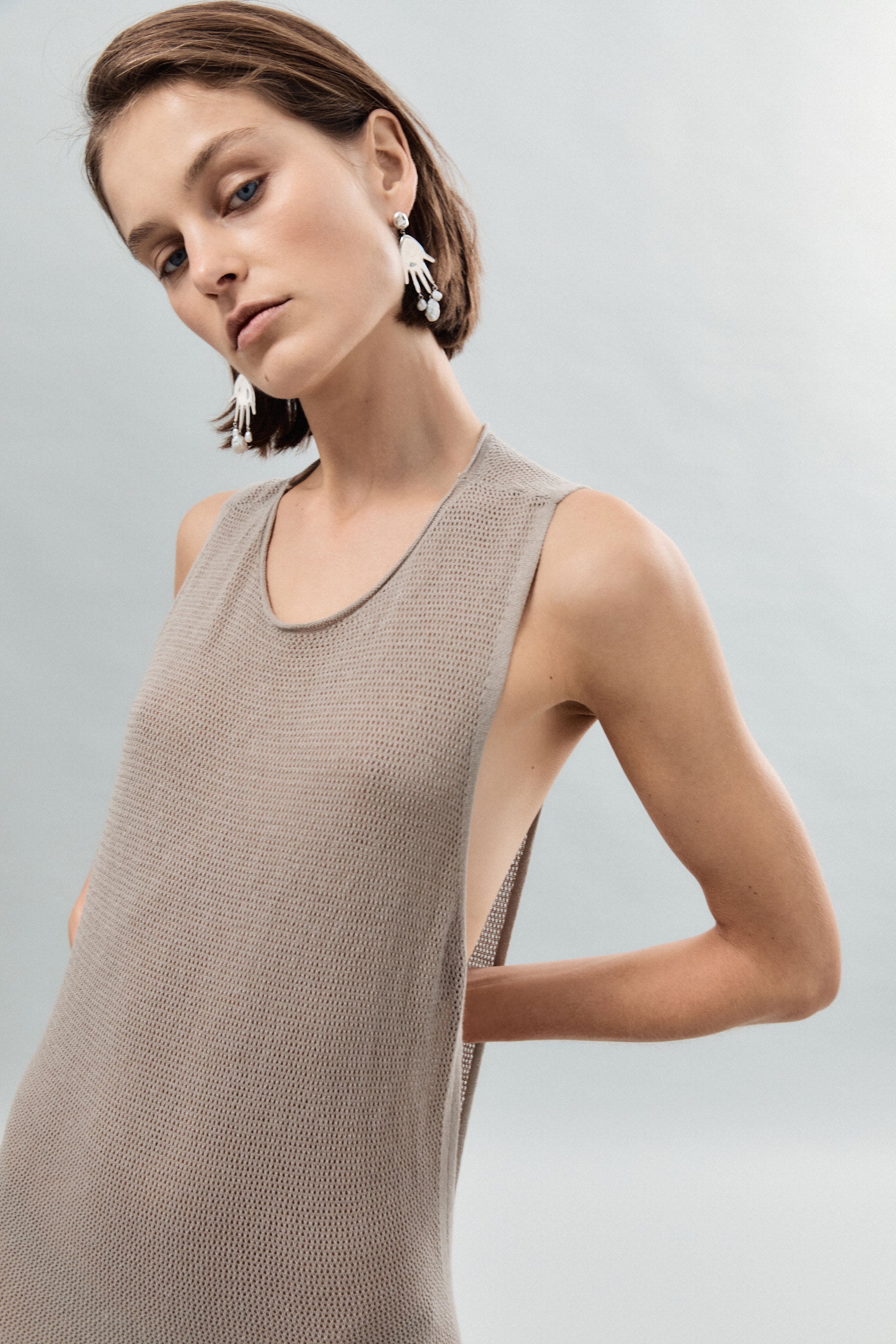 Woman wearing AGMES 0.925 sterling silver hand shaped Lee earrings with freshwater pearl drops.