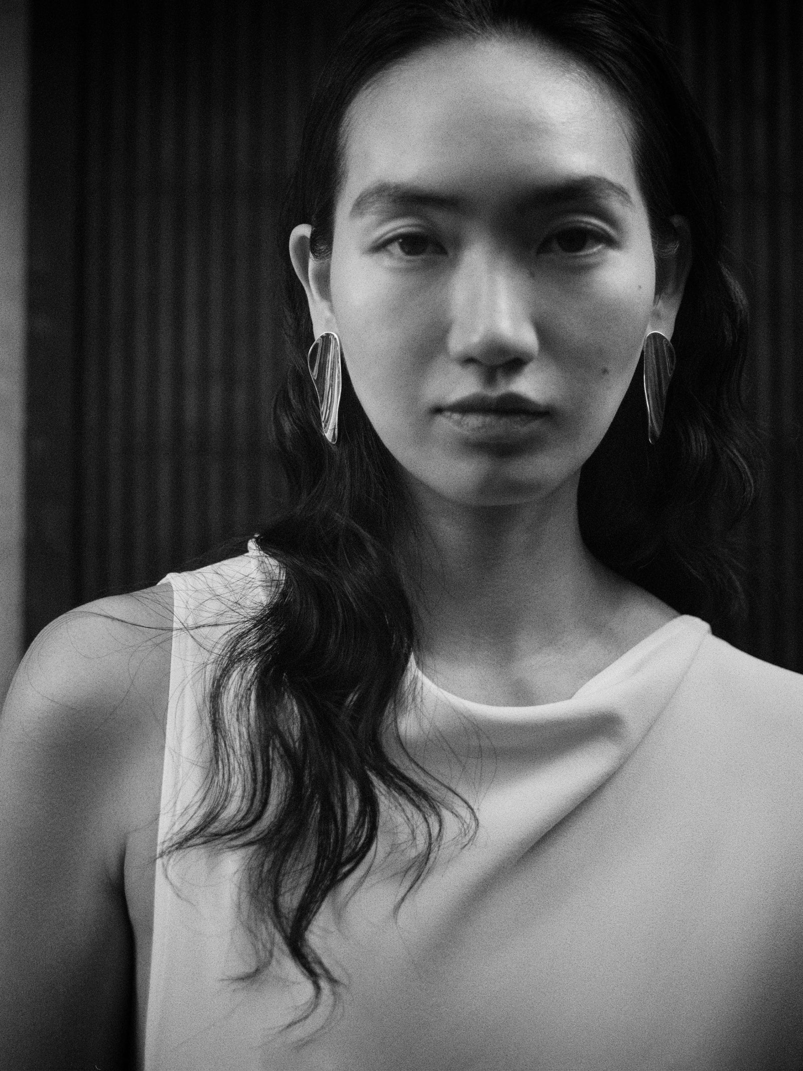 Woman wearing AGMES 0.925 sterling silver long sculpted earrings.