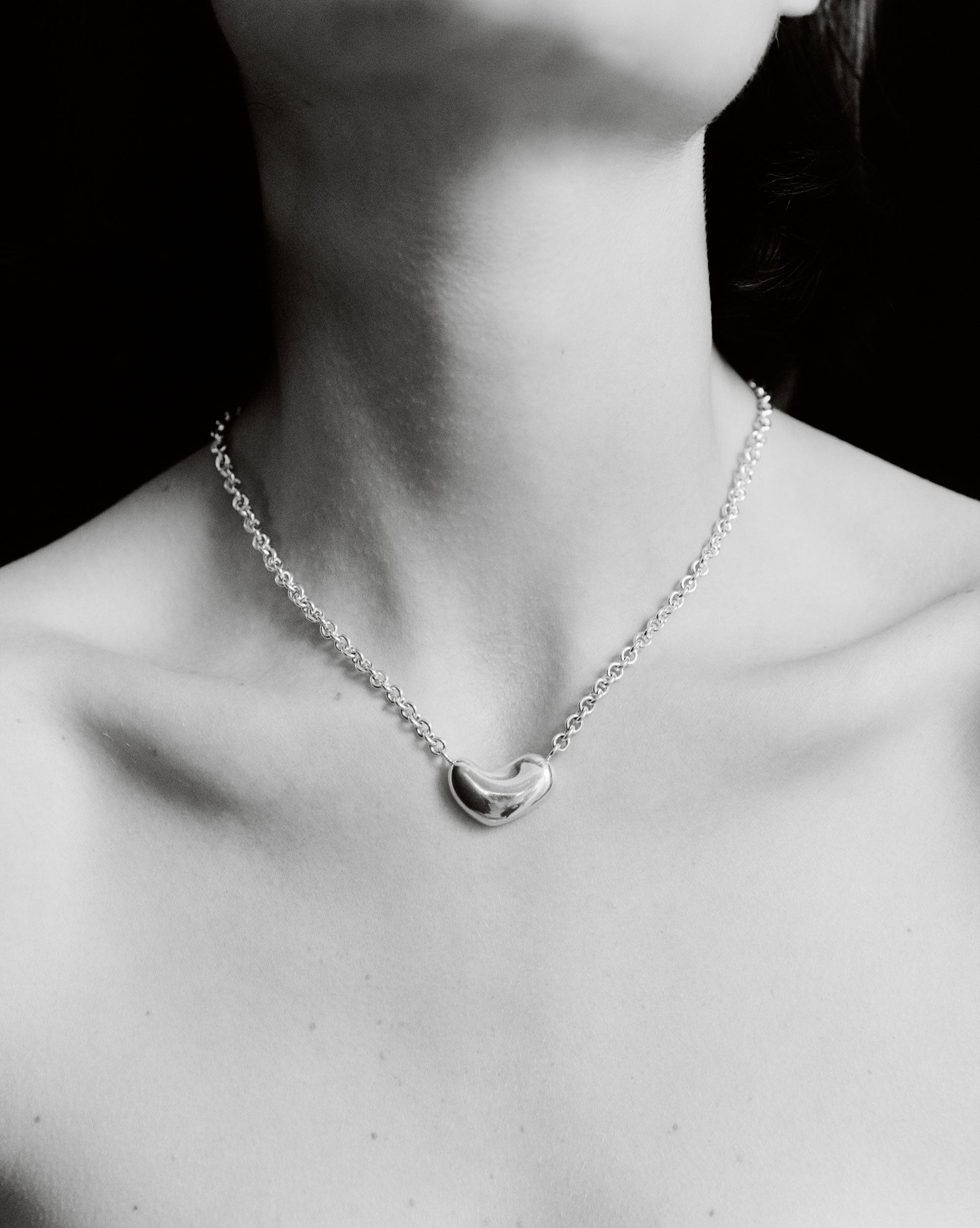 Person wearing AGMES .925 Sterling Silver Small Sculpted Heart Pendant II on chain necklace.