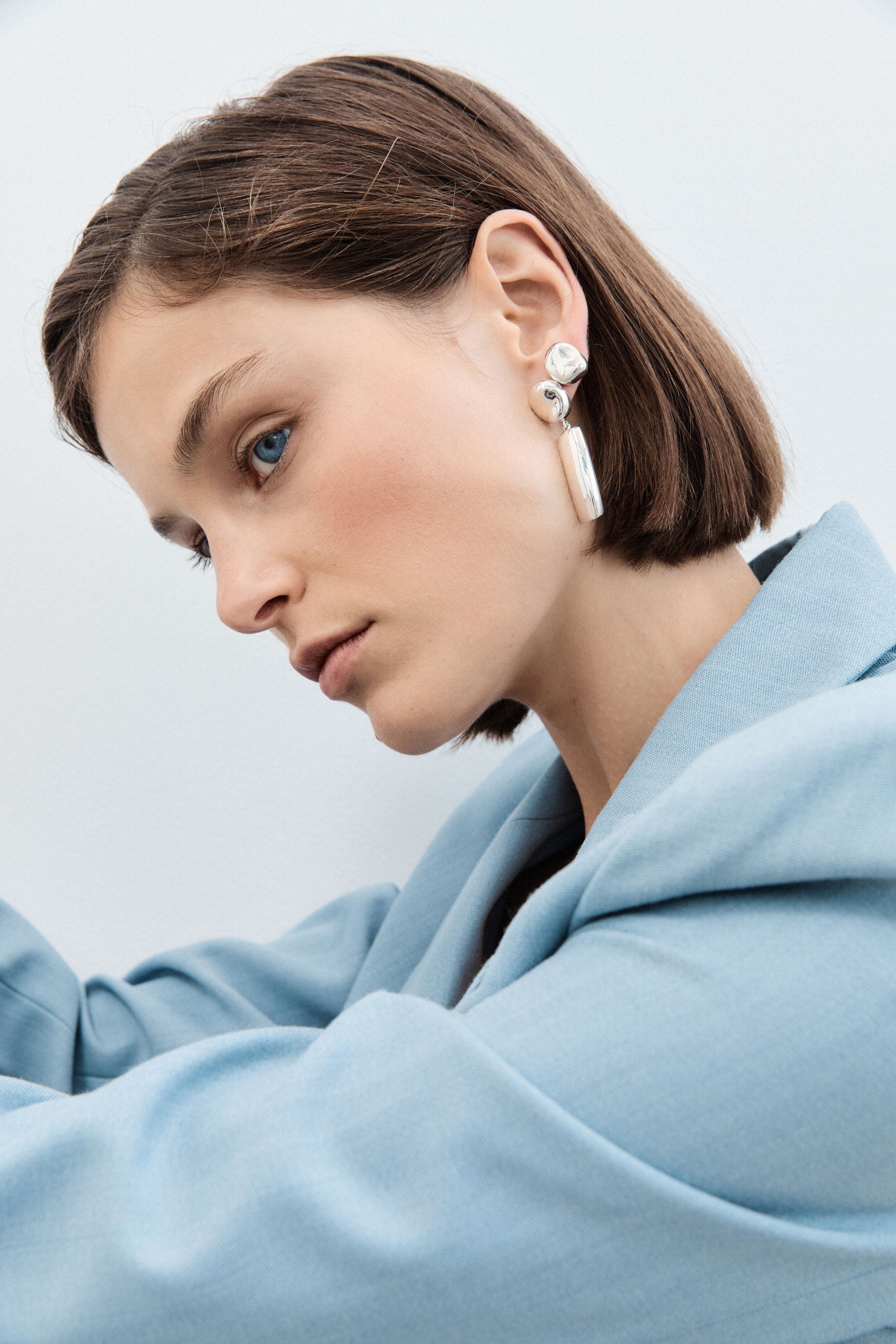 Woman wearing AGMES 0.925 sterling silver sculpted round stud earrings.