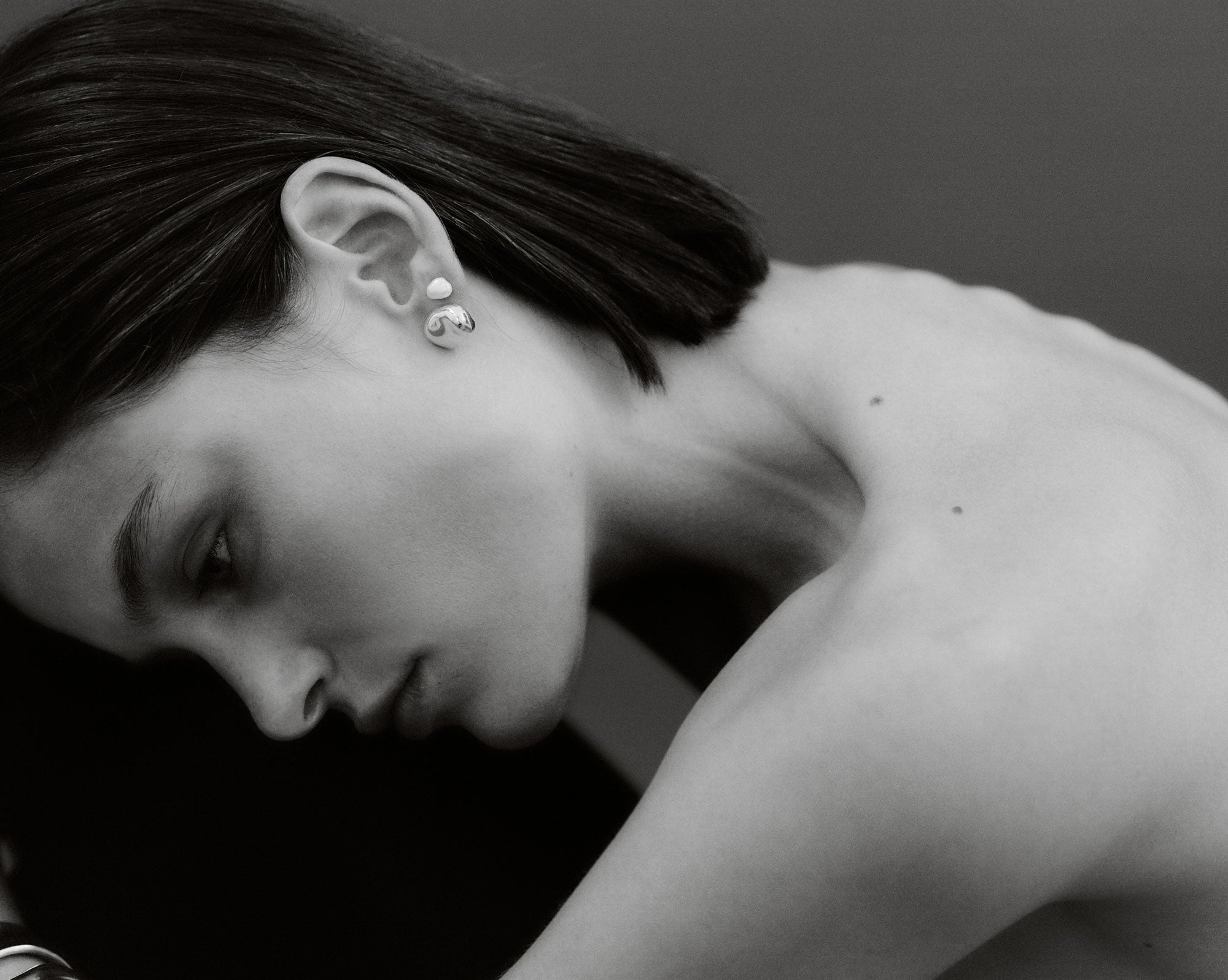 Woman wearing AGMES 18k gold vermeil sculpted round stud earrings.