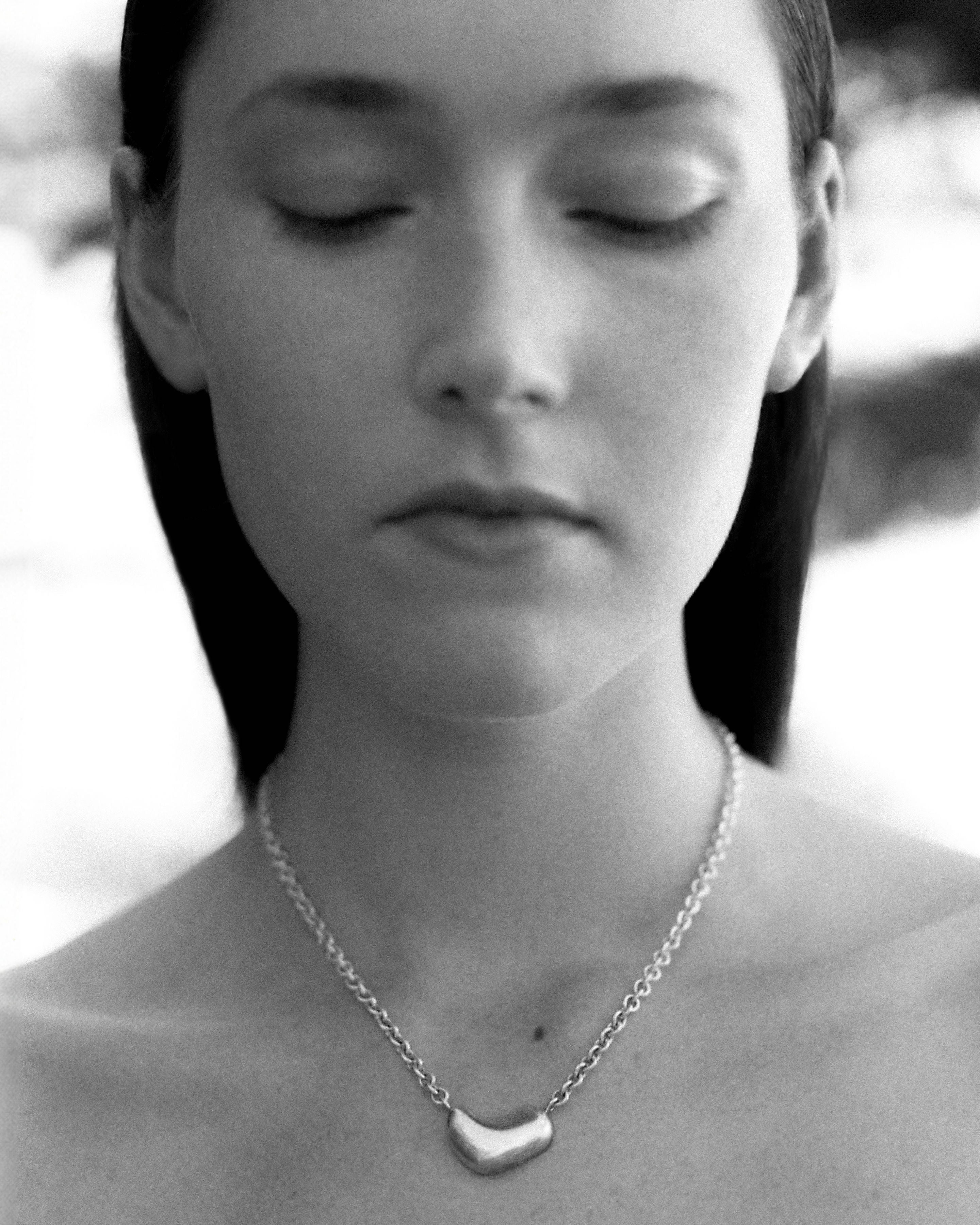 Woman wearing the AGMES .925 Sterling Silver Small Sculpted Heart Pendant II on chain necklace.