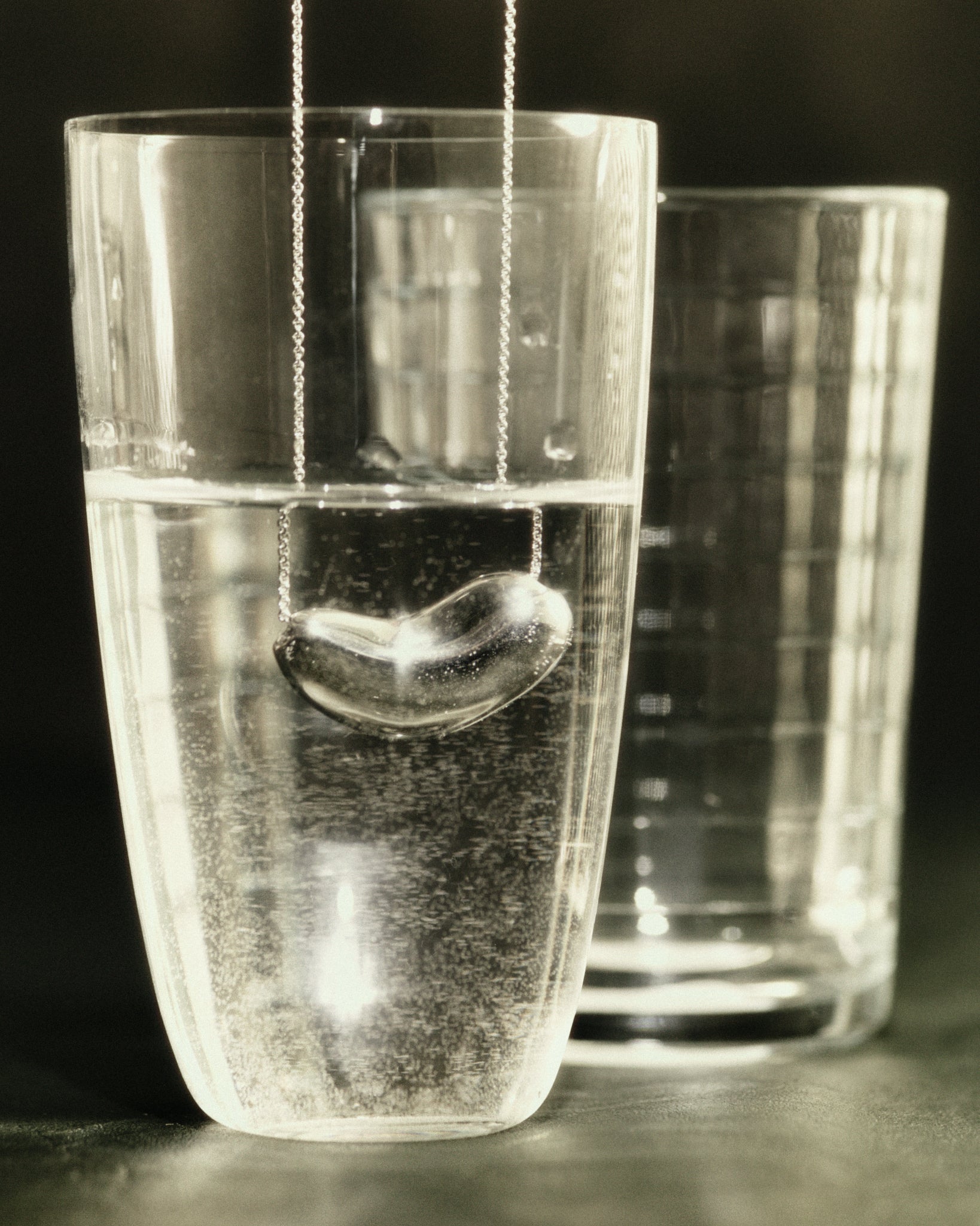 AGMES 925 Sterling Silver Small Sculpted Heart Pendant hanging in water glass.