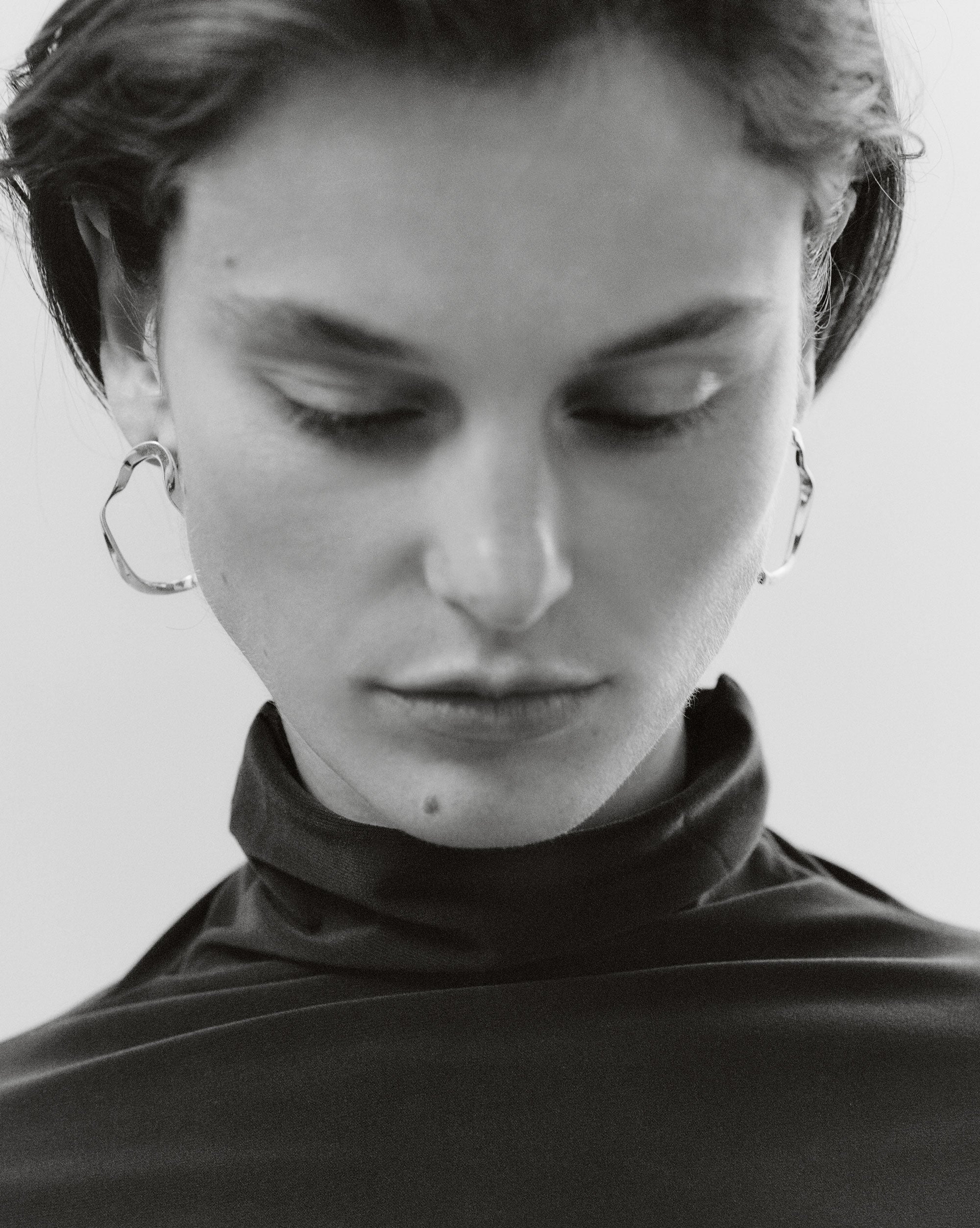 Woman wearing AGMES 18k gold vermeil sculptural wavy small round hoop earrings.