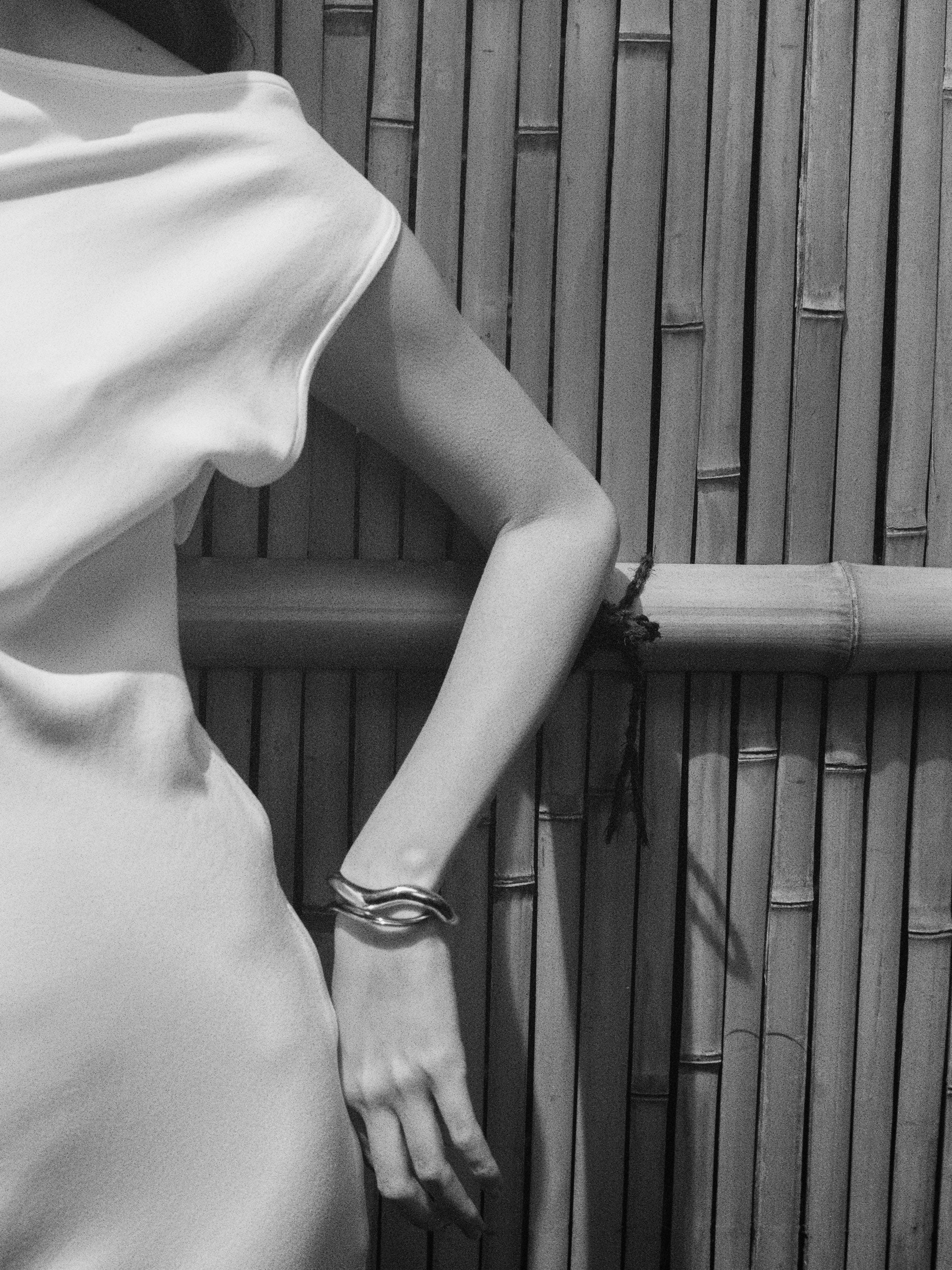 Woman wearing white dress and AGMES 0.925 sterling silver abstract medium Astrid cuff.