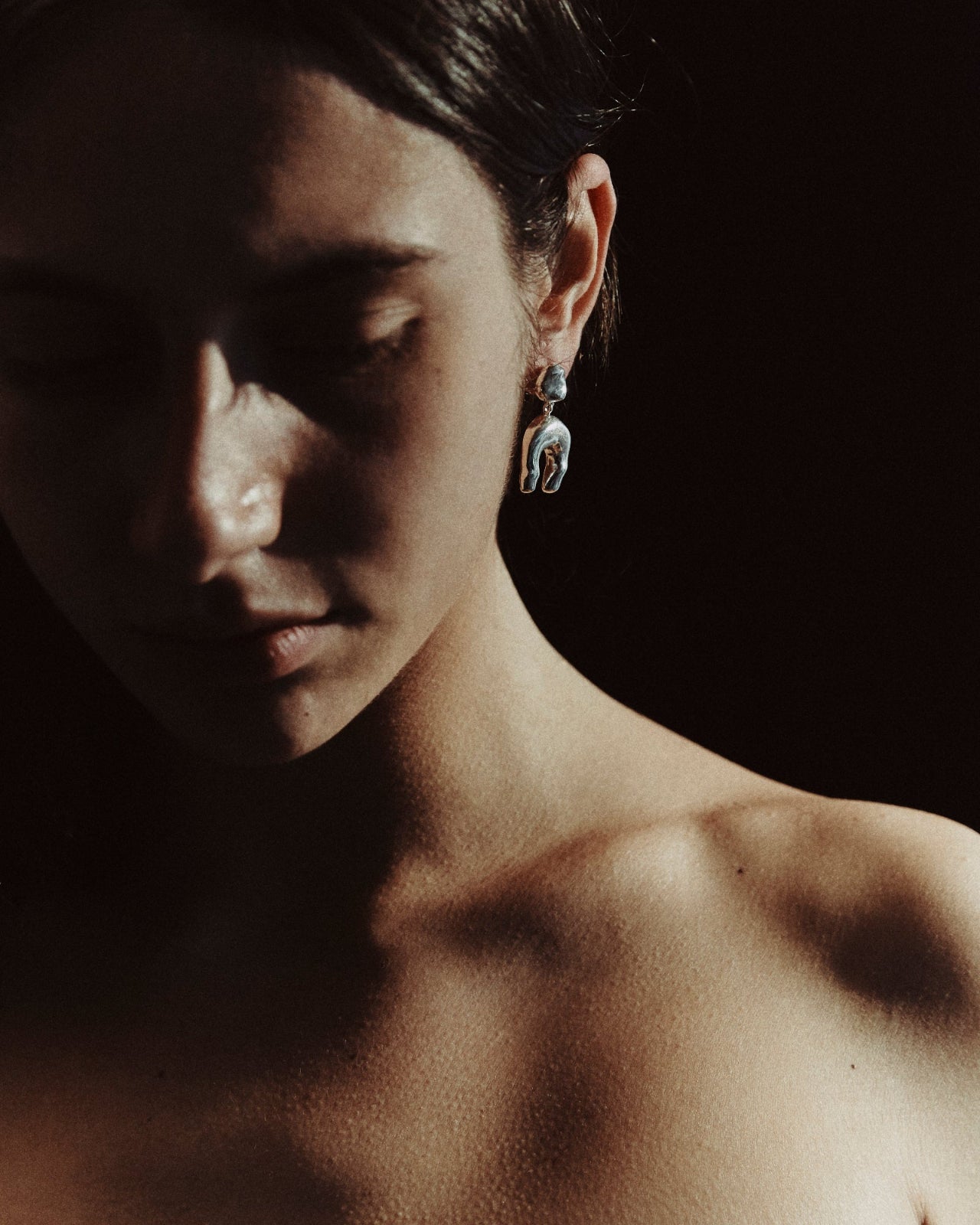 Woman wearing AGMES 0.925 sterling silver earrings with sculpted wishbone drop.