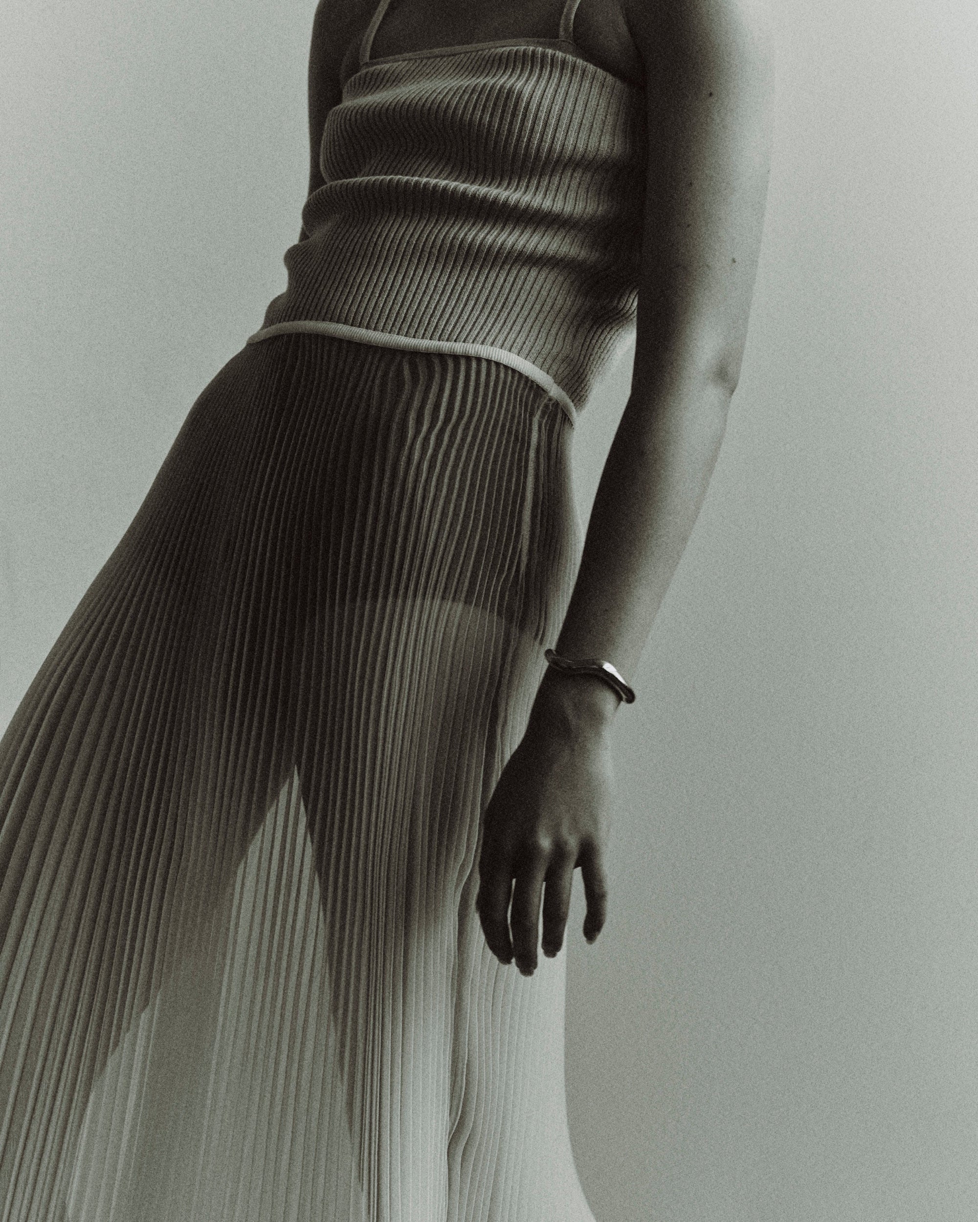 Woman in pleated sheer dress wearing AGMES 0.925 sterling silver abstract medium Astrid cuff.