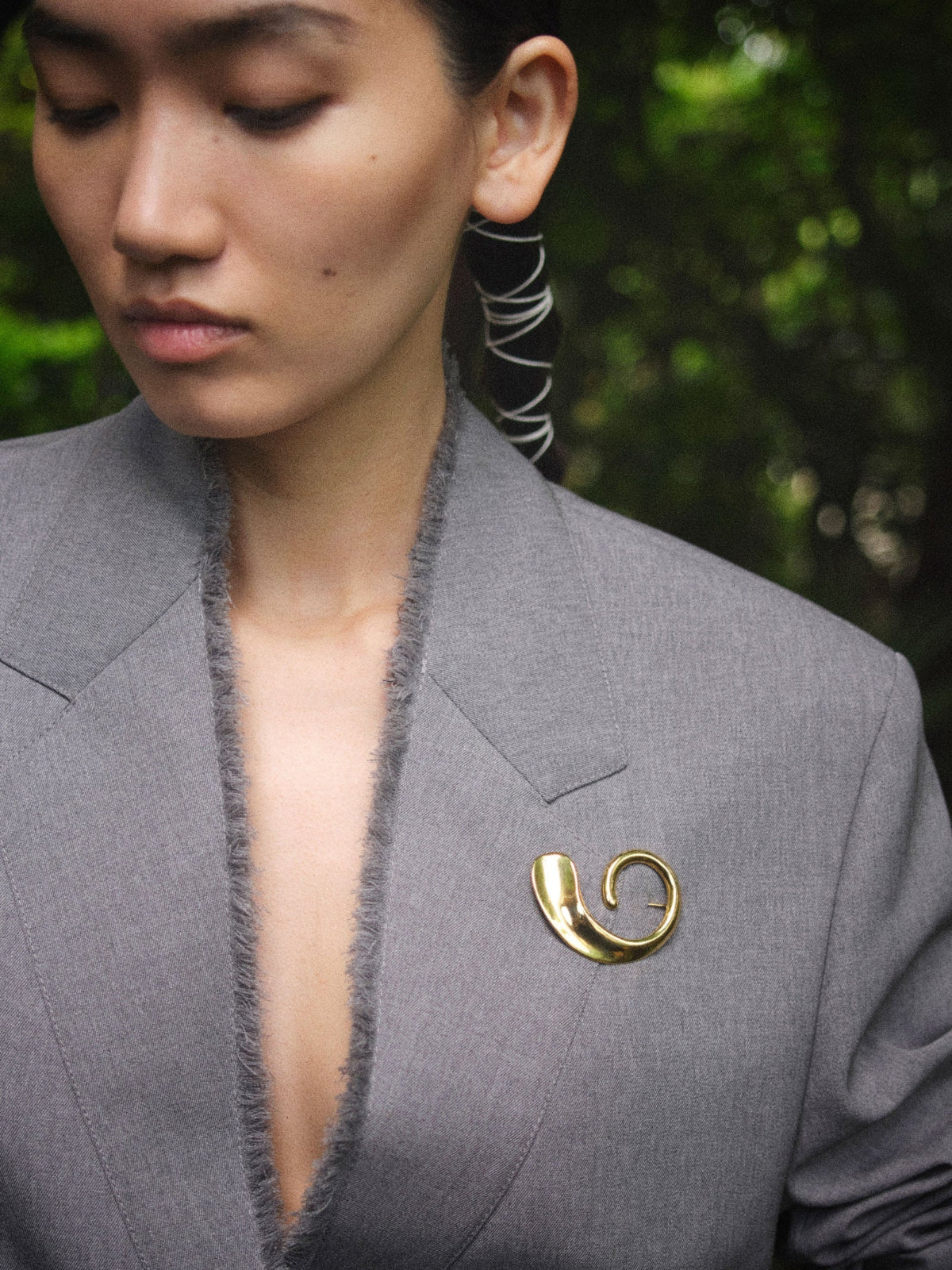 Woman wearing AGMES 18k gold vermeil Marta Brooch on grey blazer.