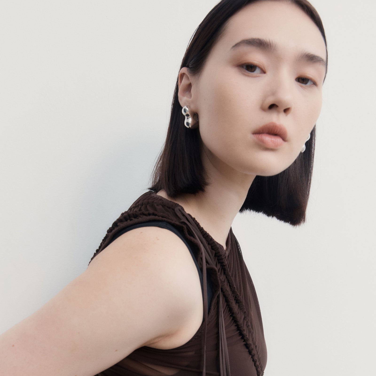 Woman wearing AGMES 0.925 sterling silver sculpted bubble hoop earrings. Simone Bodmer-Turner.