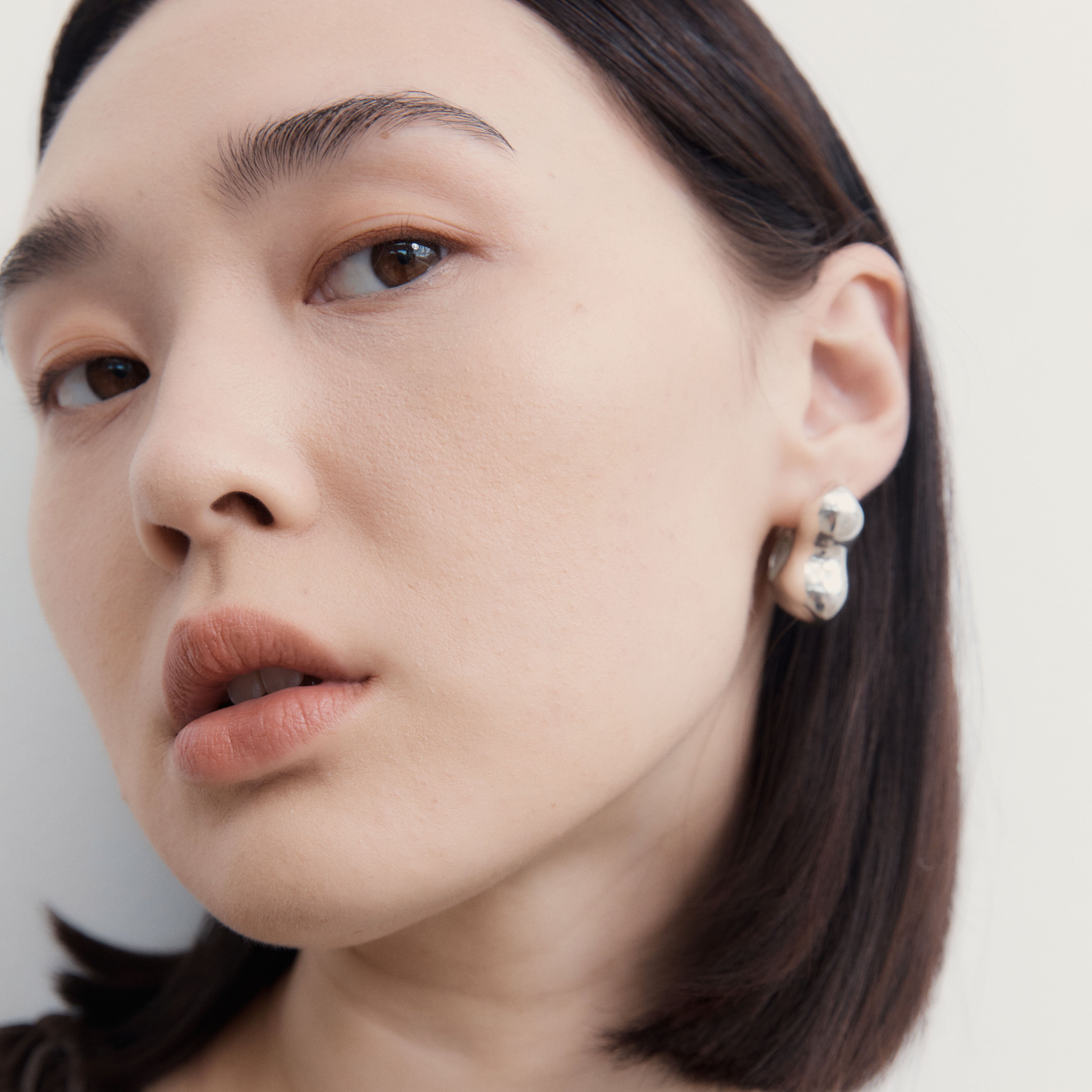 Woman wearing AGMES 0.925 sterling silver sculpted bubble hoop earrings. Simone Bodmer-Turner.