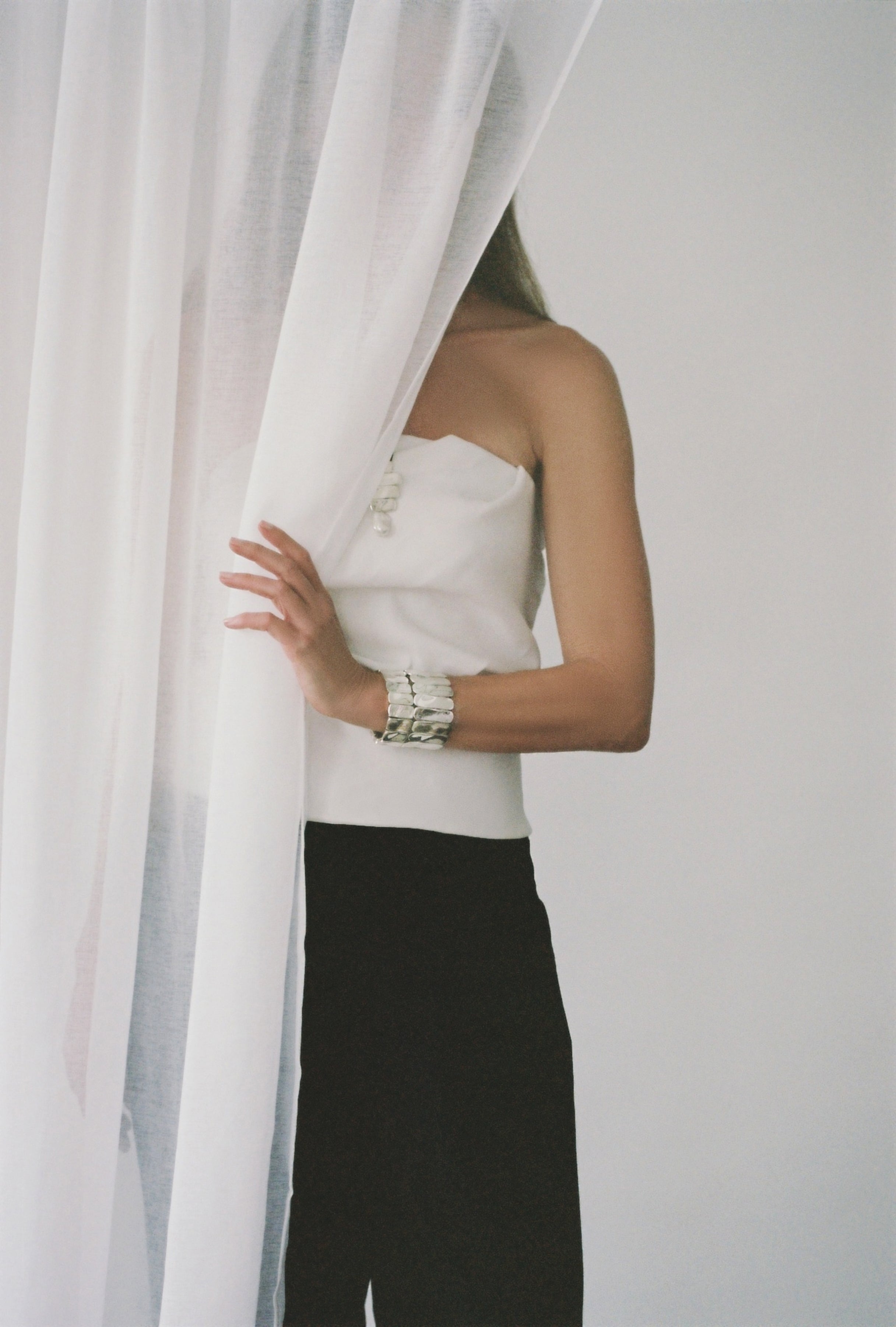 Woman wearing whit top, black pants, and AGMES 0.925 sterling silver Ilona Bracelet with adjustable elastic band.