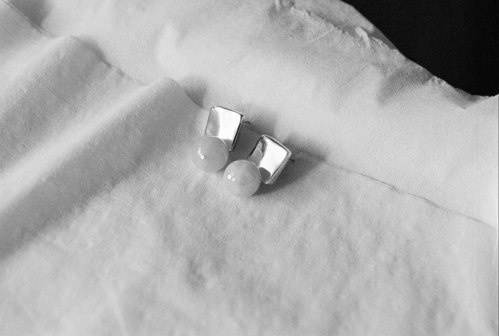 AGMES.925 sterling silver and rose quartz Luca Earrings. Photographed in black and white sitting on a pieces of white fabric.