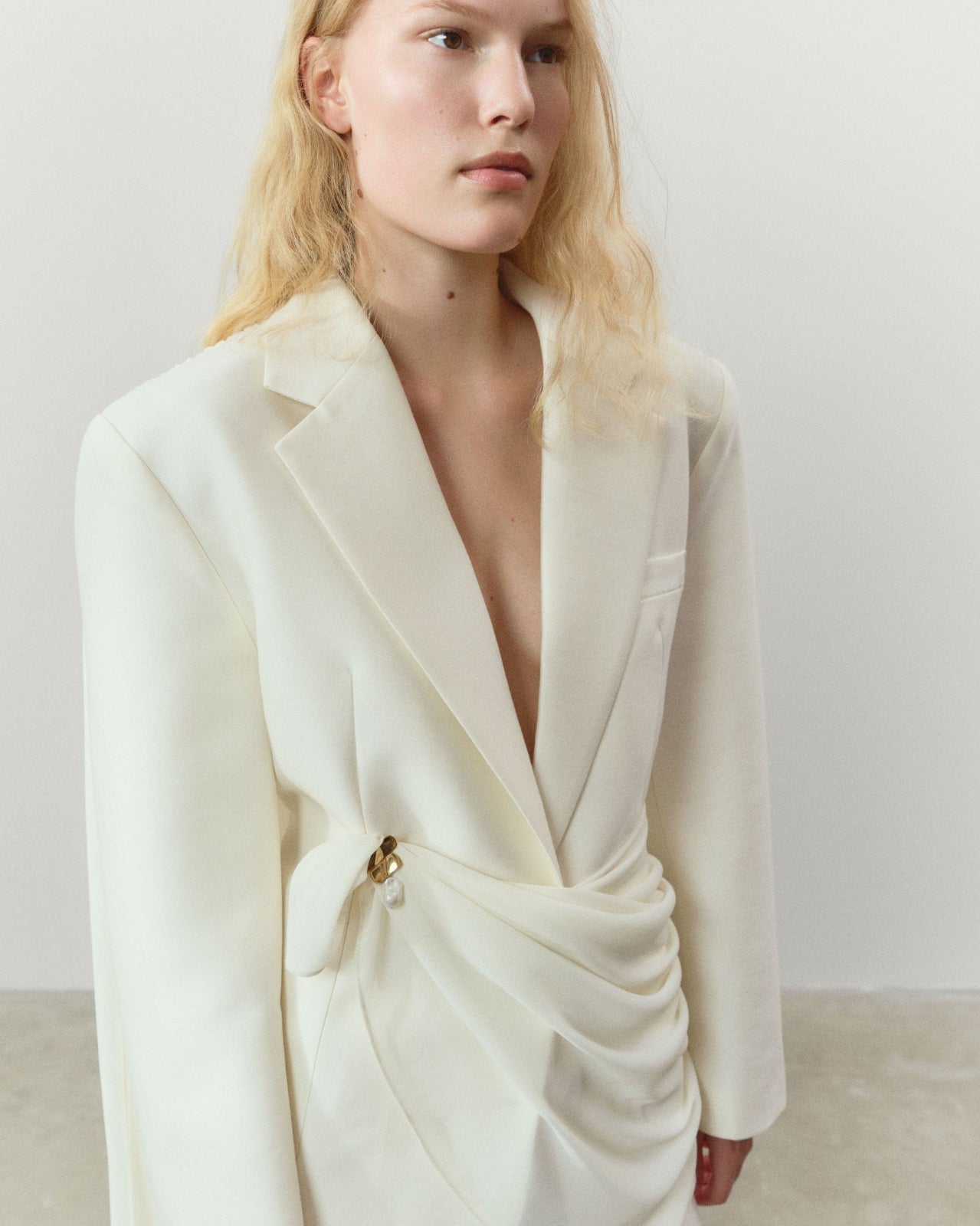 Model wearing AGMES 18k gold vermeil and baroque freshwater pearl Baroque Ilona Brooch on white blazer.