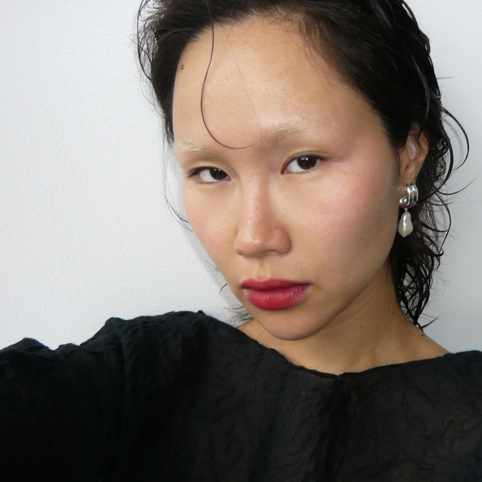 Woman wearing AGMES 0.925 sterling silver baroque Juliette clip on hoop earrings with freshwater pearl drop.