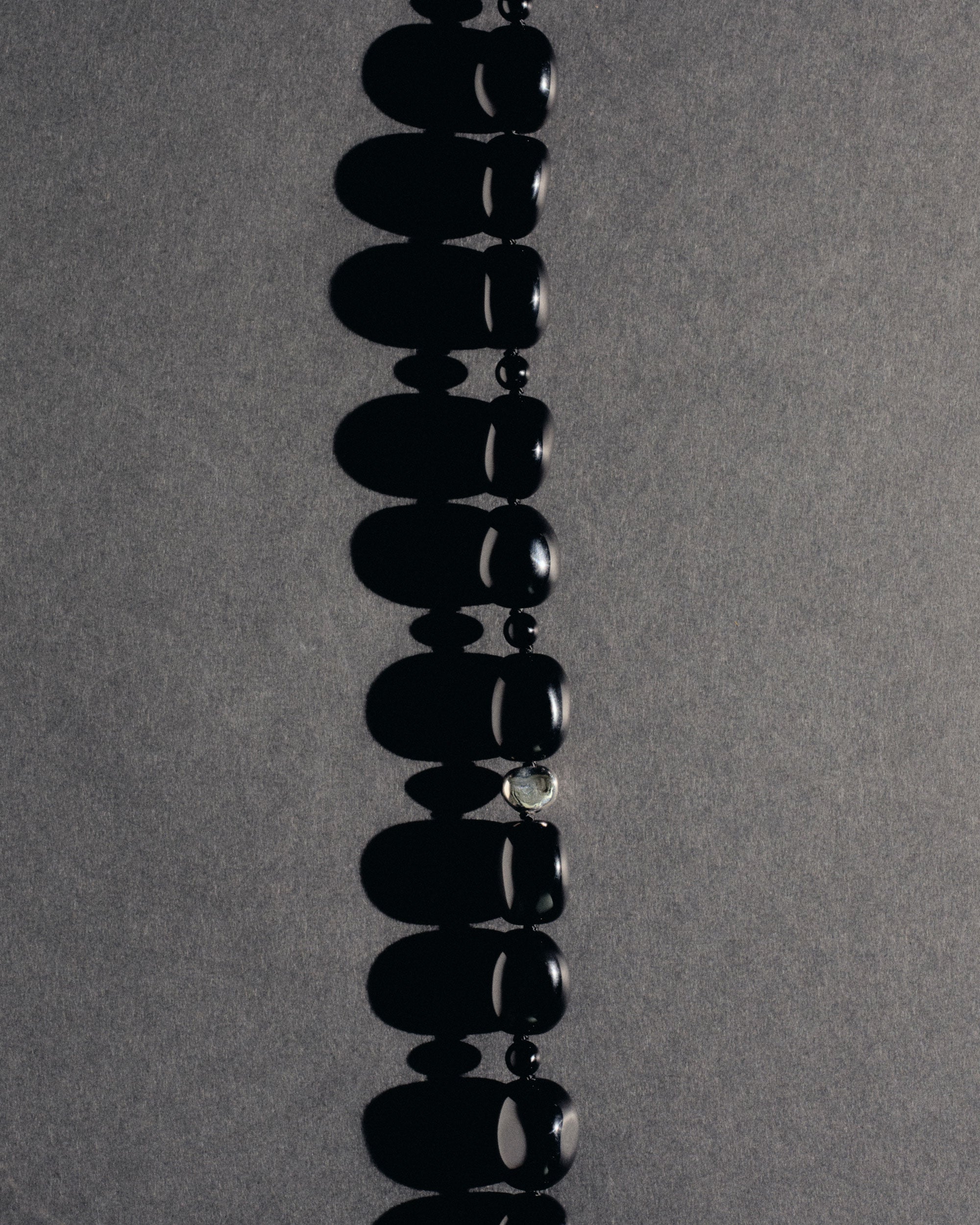 Black onyx beaded necklace with .925 sterling silver accent on grey background