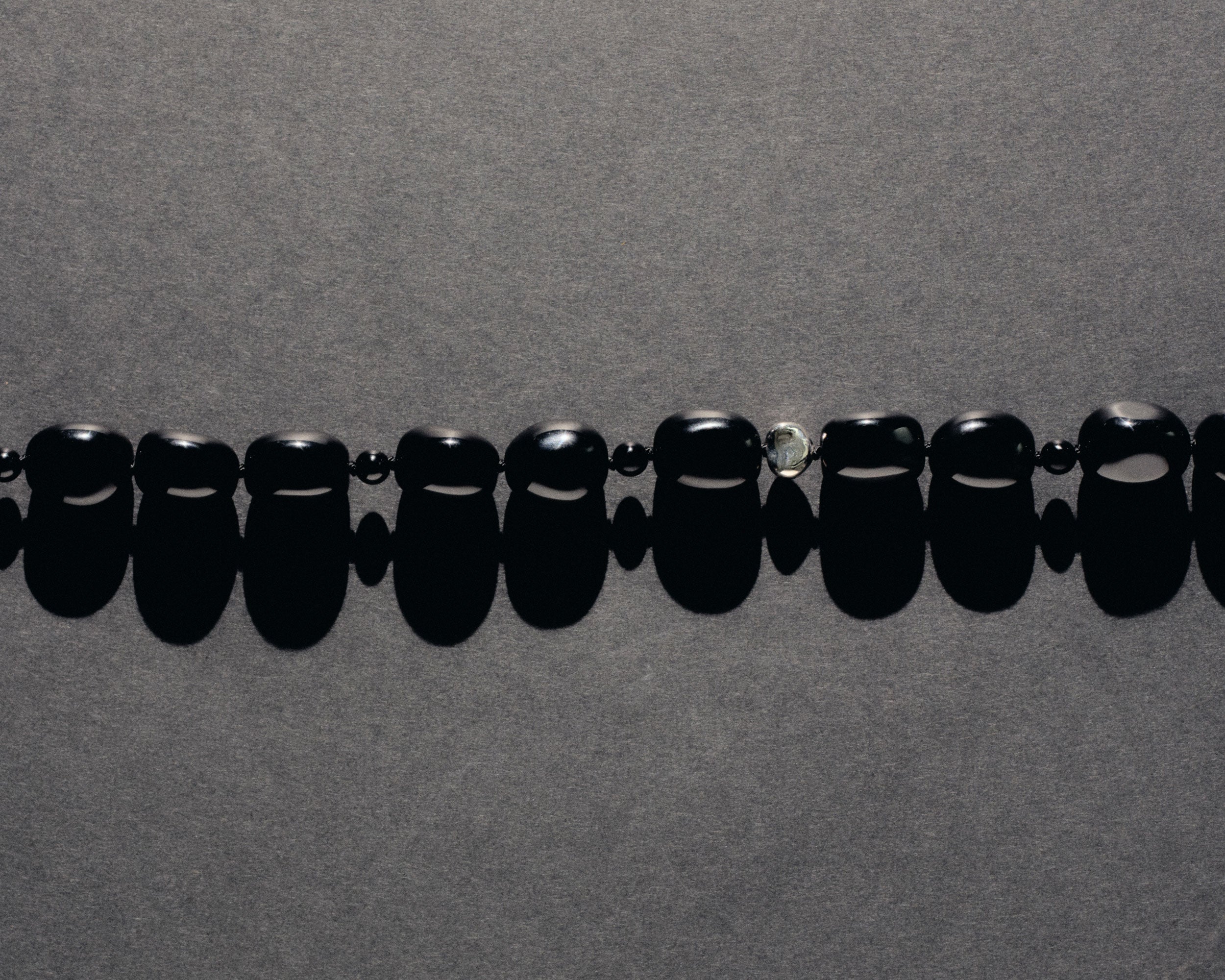 Black onyx beaded necklace with .925 sterling silver accent on grey background