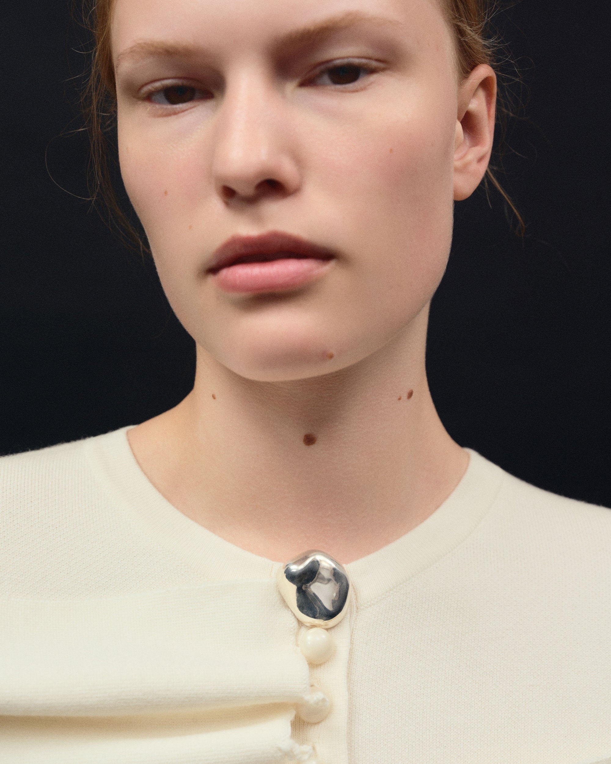 Person wearing AGMES 0.925 Sterling Silver round Gia Brooch on white sweater.