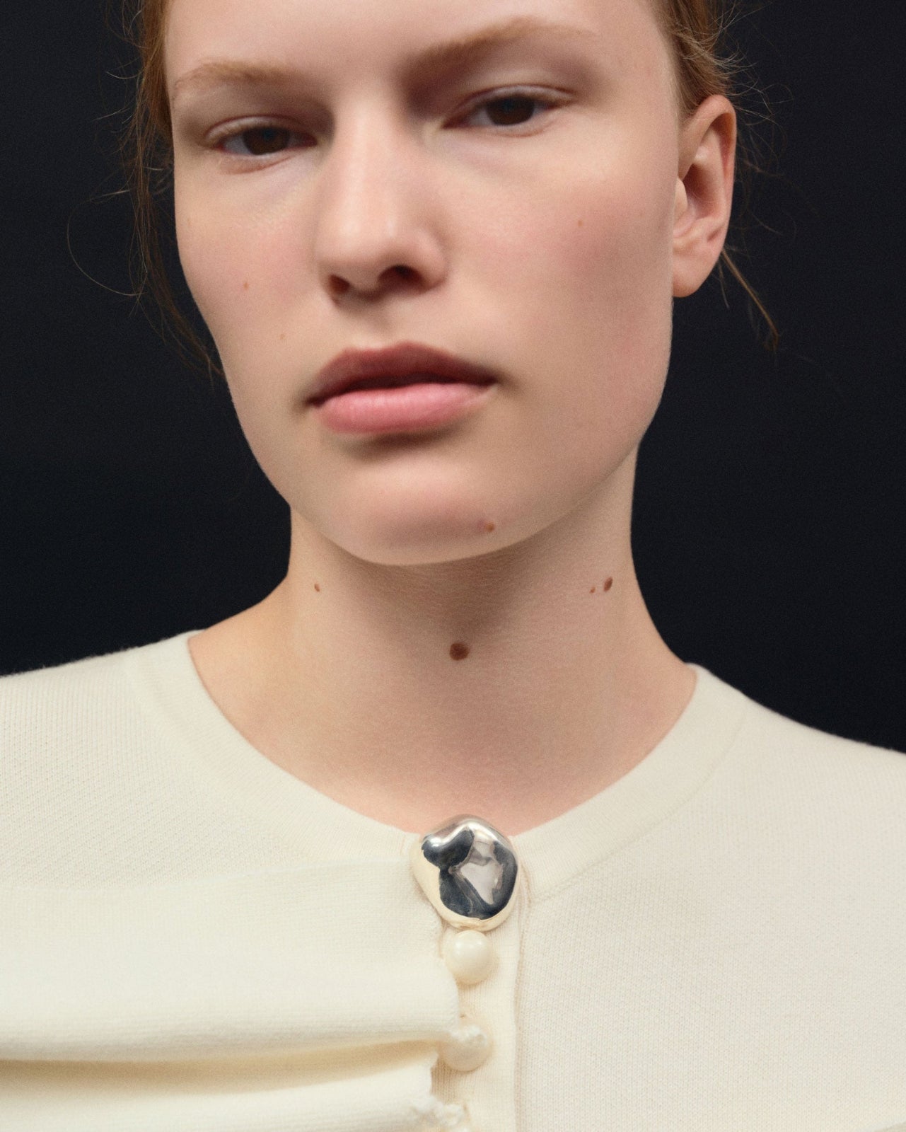 Person wearing AGMES 0.925 Sterling Silver round Gia Brooch on white sweater.