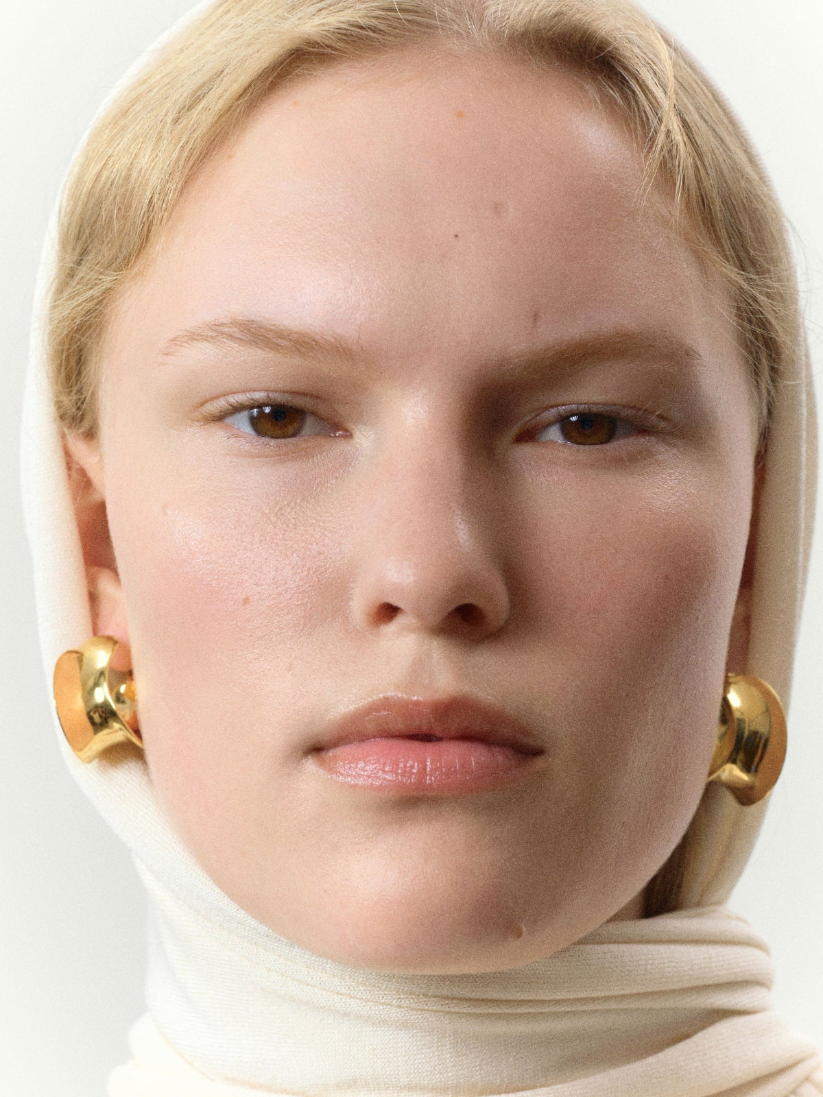 Woman wearing AGMES 18k gold vermeil Laila twist hoop earrings.