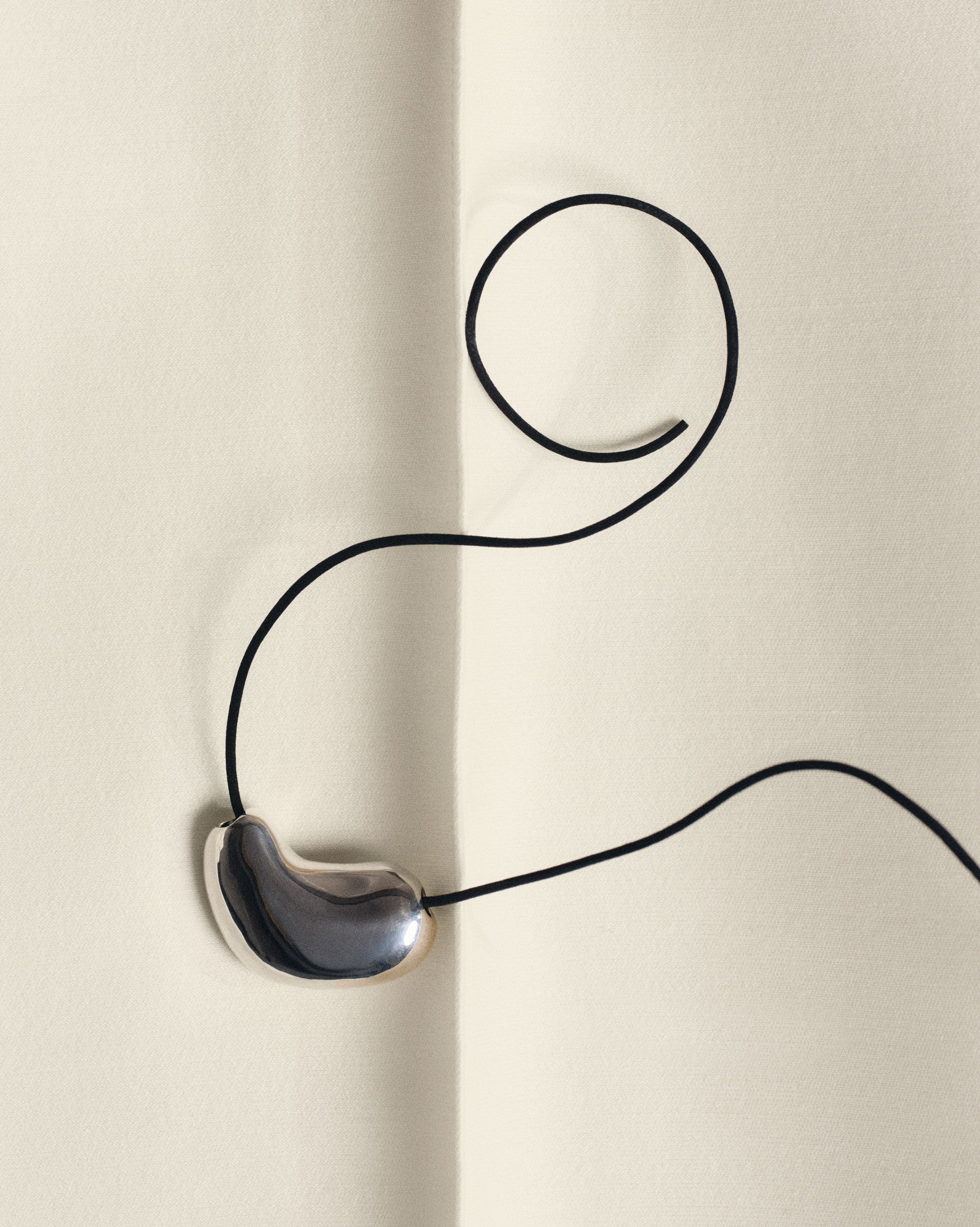 AGMES .925 sterling silver sculpted heart pendant necklace on black suede cord on white background.