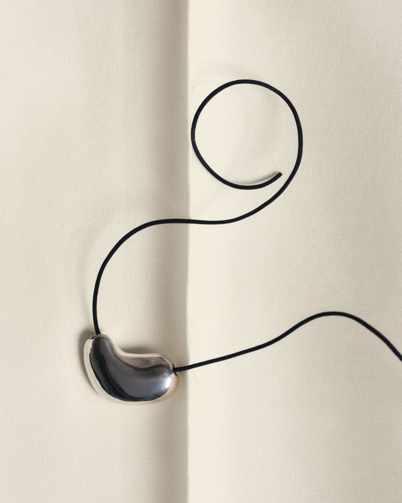 AGMES .925 sterling silver sculpted heart pendant necklace on black suede cord on white background.