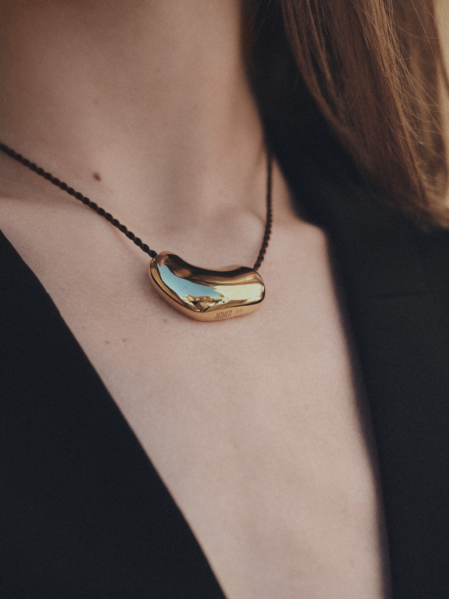 Person wearing AGMES 18k Gold Vermeil Sculpted Heart Pendant on Chocolate Silk Cord.