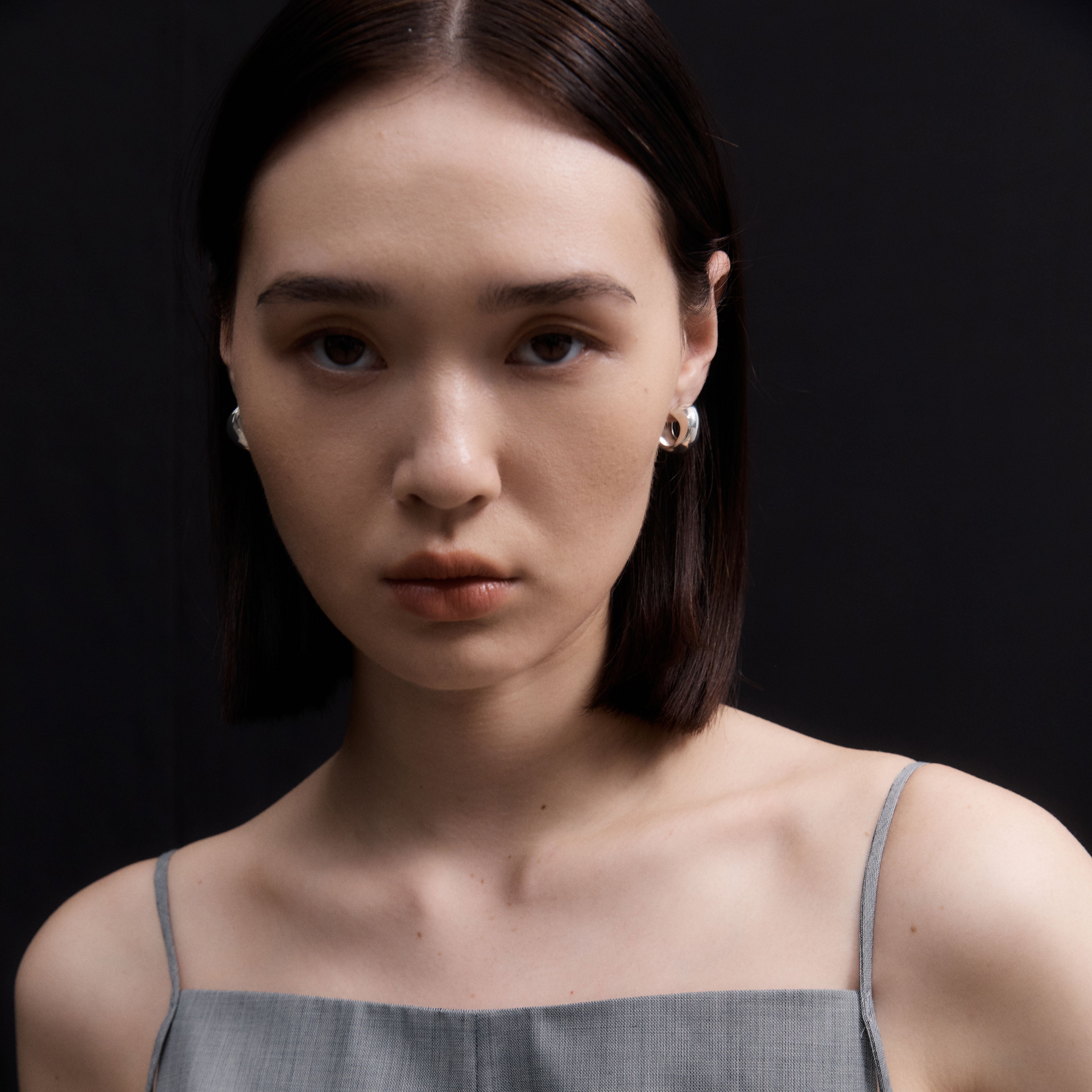 Woman wearing AGMES 0.925 sterling silver small hoop earrings.