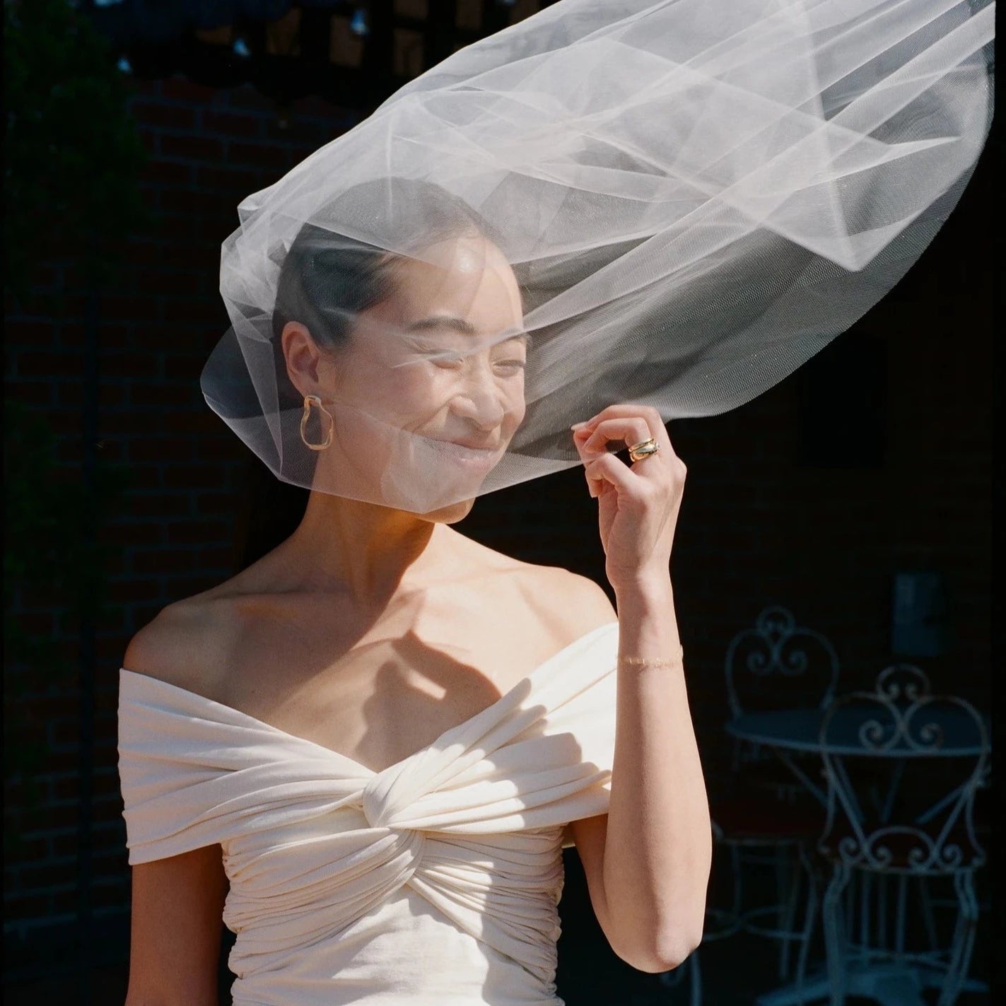Woman wearing AGMES 18k gold vermeil sculptural wavy small round hoop earrings.