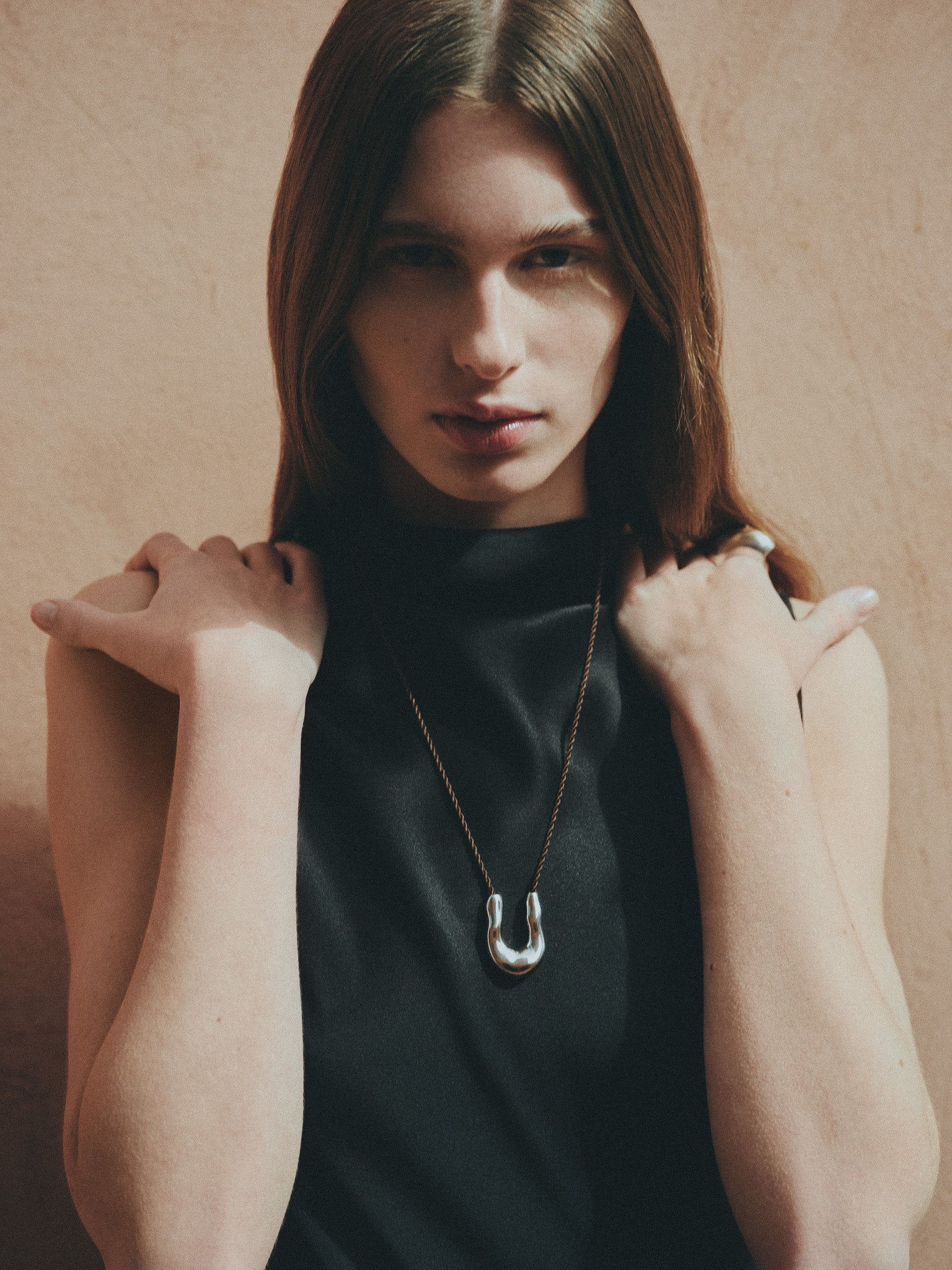 Woman Wearing AGMES 0.925 sterling silver wishbone pendant on chocolate silk cord.