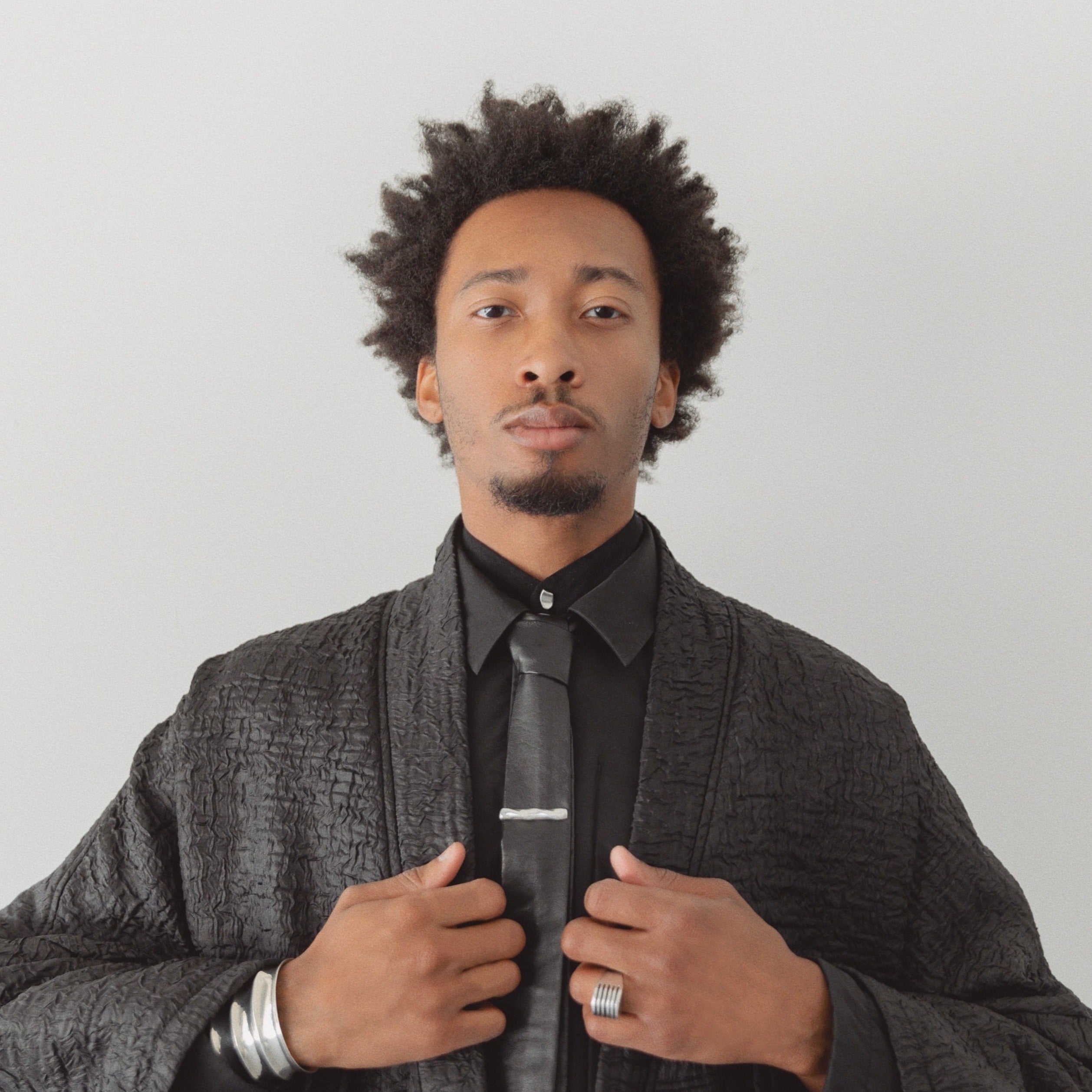 Man wearing the AGMES .925 Sterling Silver Sum of Parts Mini Brooch on black shirt.