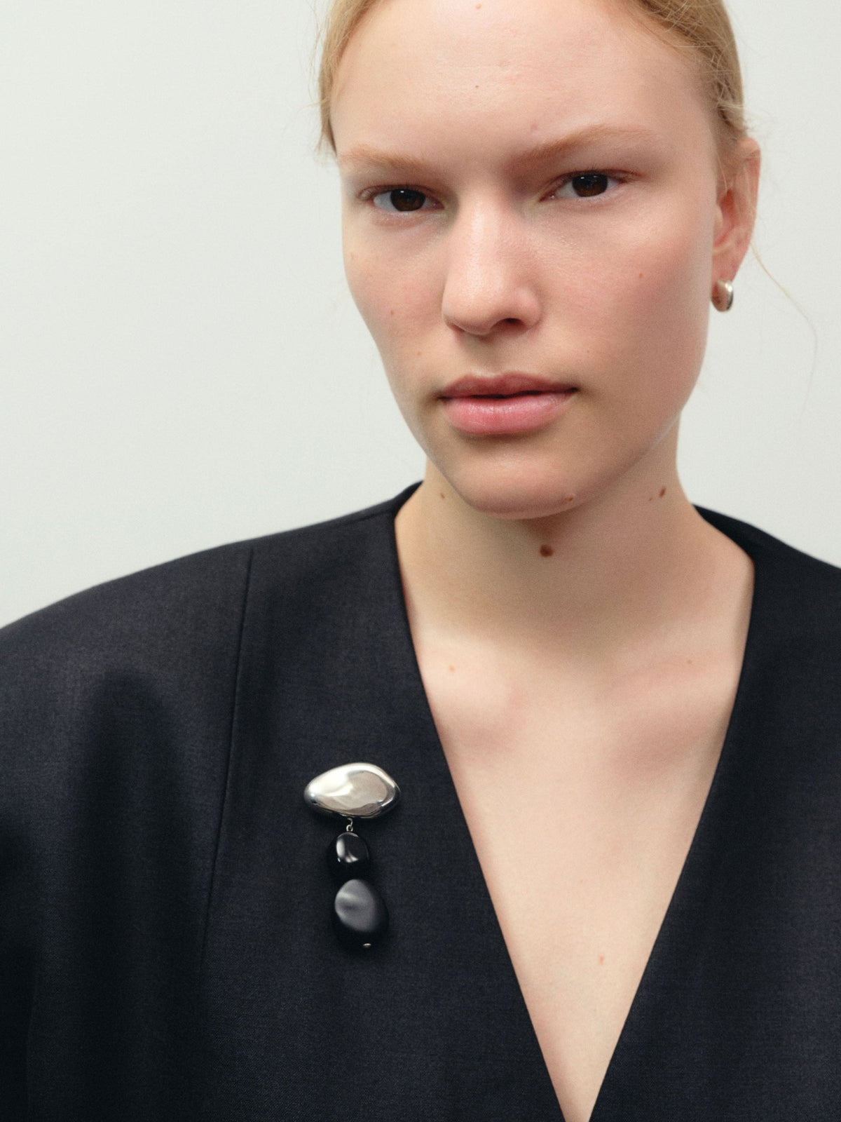 Model wearing AGMES .925 sterling silver Small Dahlia Hoops and onyx Tess Brooch on black blouse.
