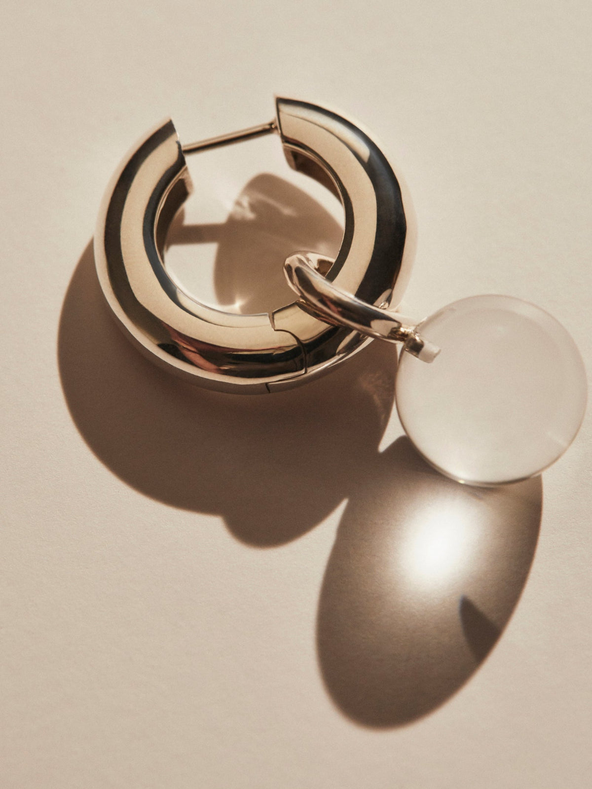 AGMES .925 sterling silver and clear quartz Sonia Hinged Hoop earring on white background with shadow.