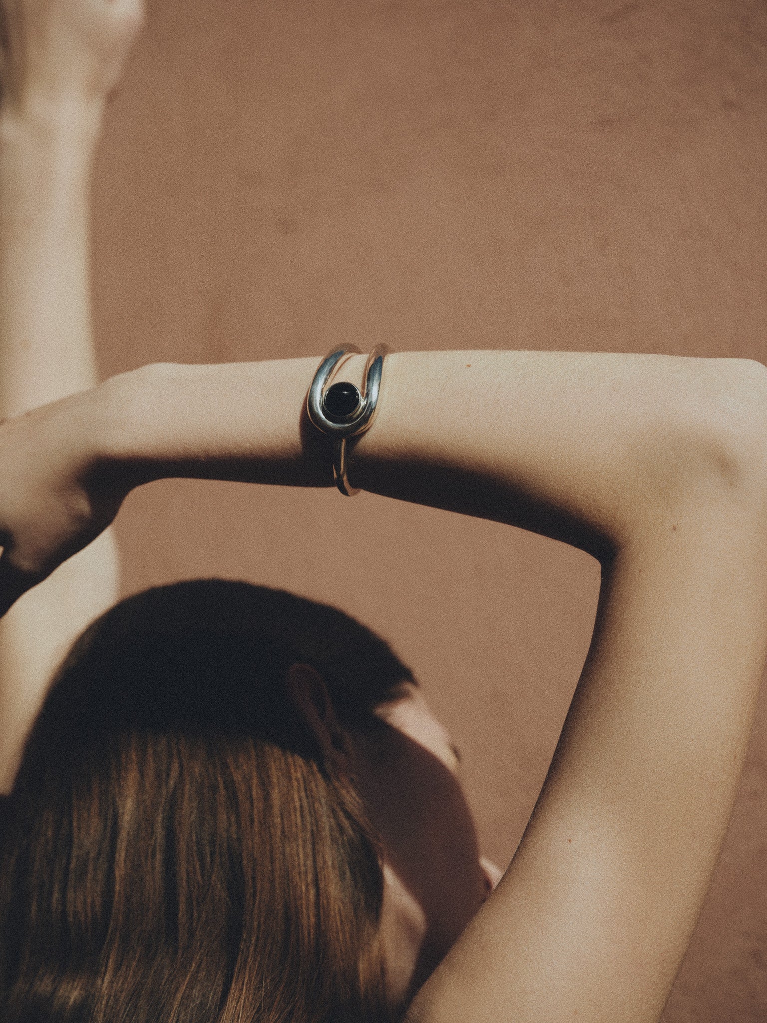 Woman wearing AGMES 0.925 sterling silver Becky cuff bracelet with lapis stone in front of natural background.