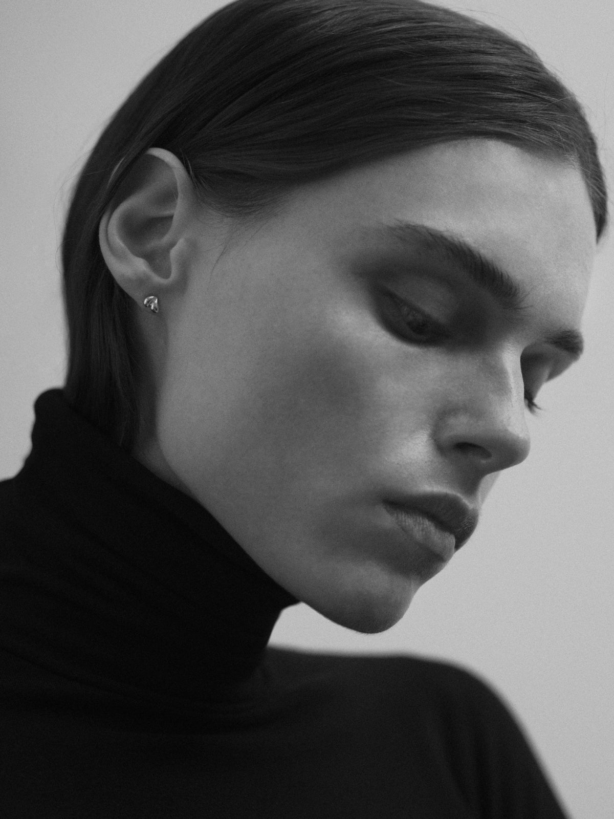 Model wearing AGMES .925 sterling silver mini heart shaped Lilla stud earrings. Image in black and white.