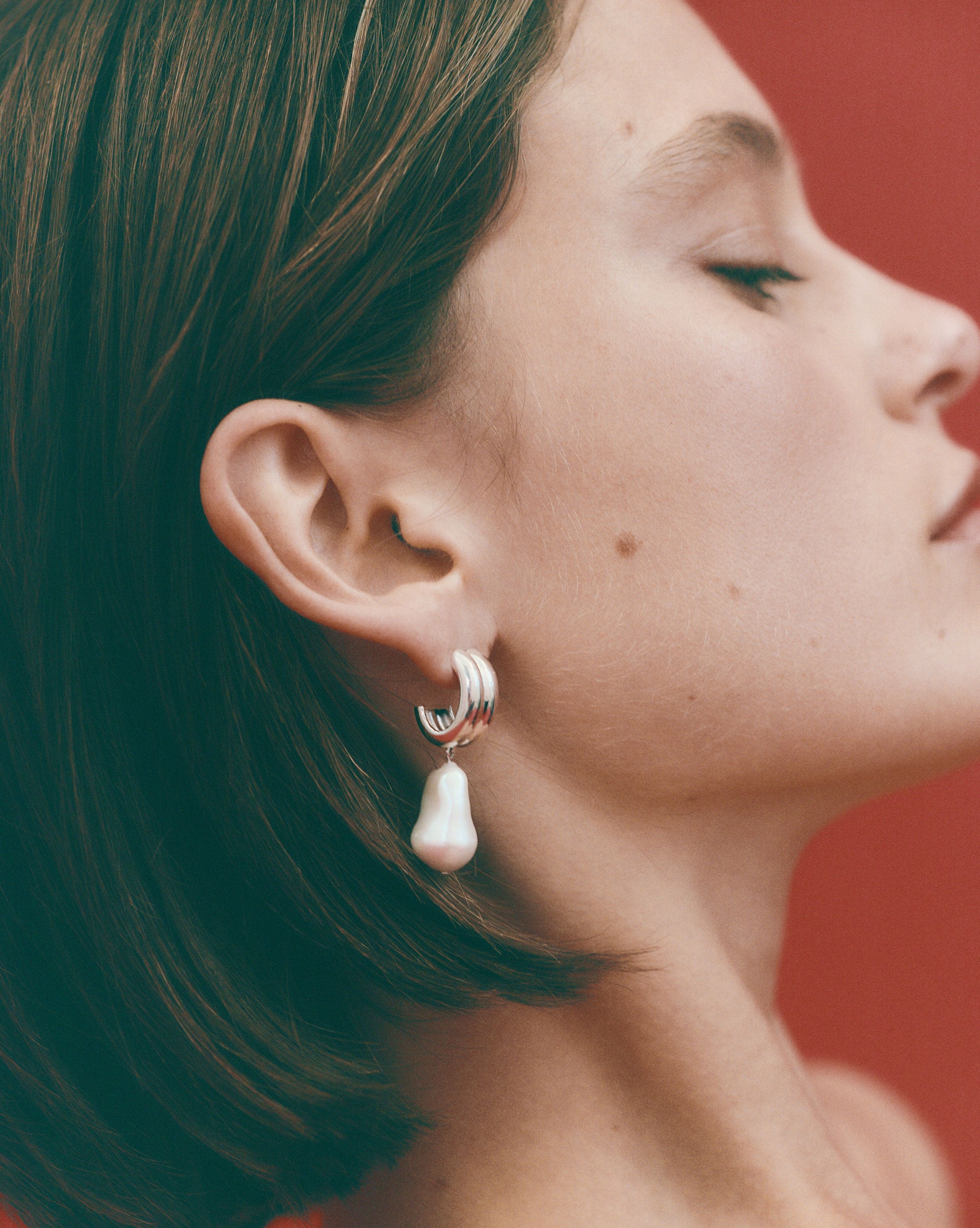 Woman wearing AGMES 0.925 sterling silver baroque Juliette earrings with freshwater pearl drop.