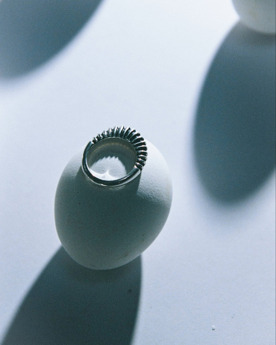 .925 sterling silver bertrand ring laying flat on egg, abstract still life