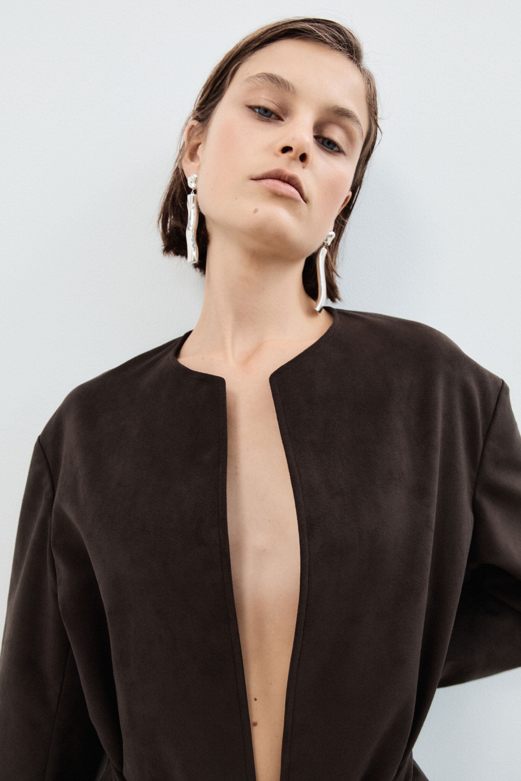 Woman wearing AGMES 0.925 sterling silver long sculptural drop earrings with silver top.