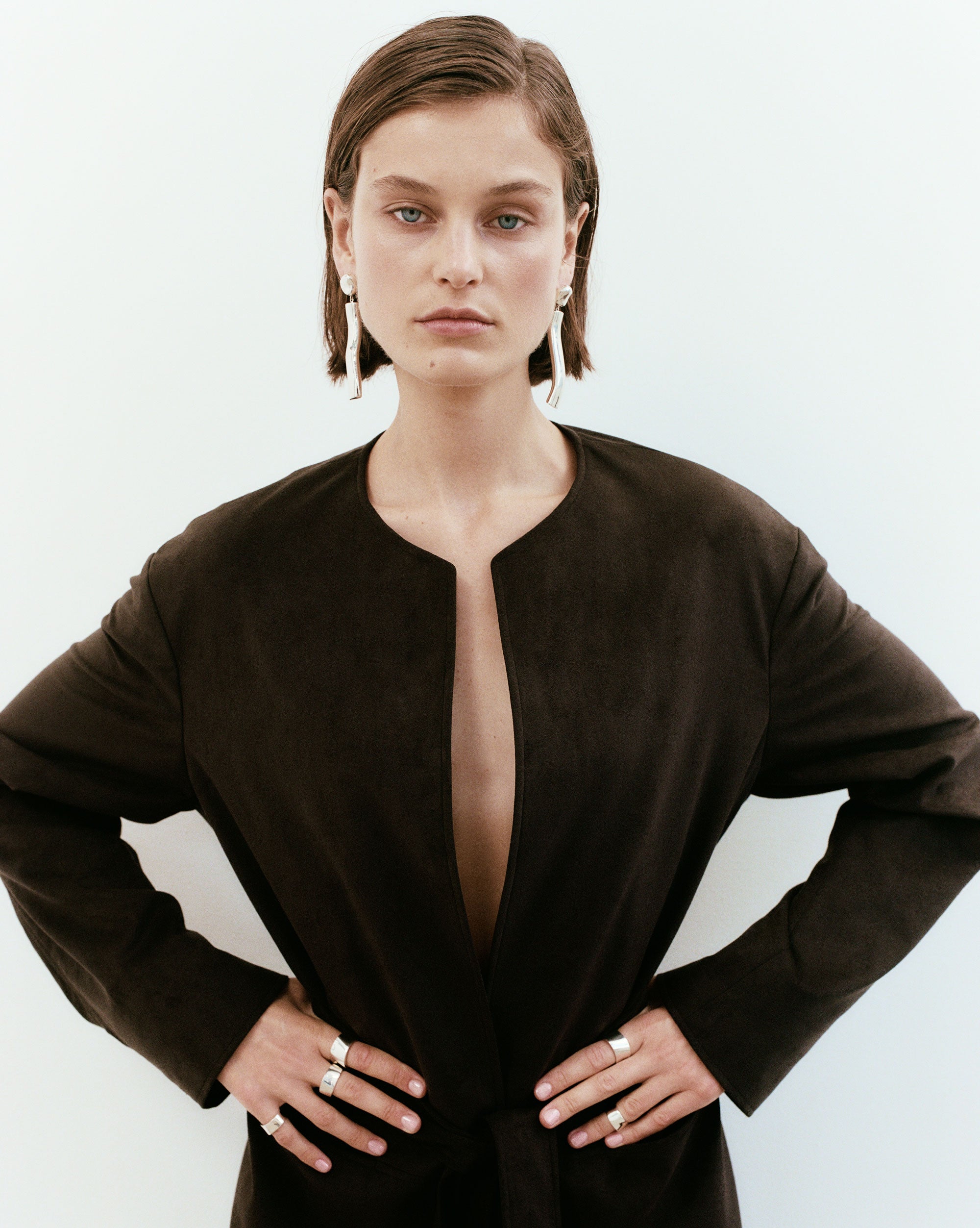 Woman wearing AGMES 0.925 sterling silver long sculptural drop earrings with silver top.