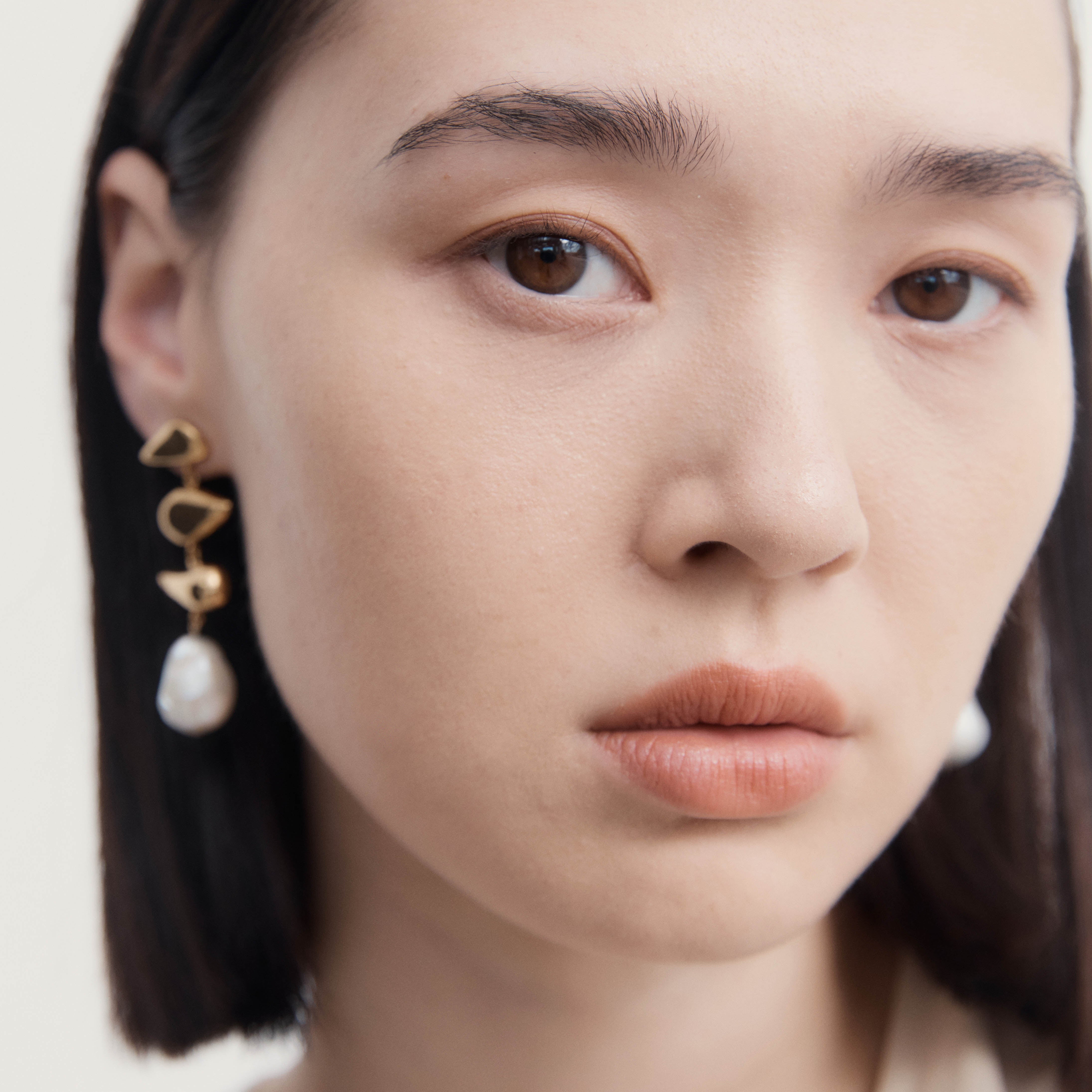 Woman wearing AGMES 18K gold vermeil drop pearl Flora earrings.