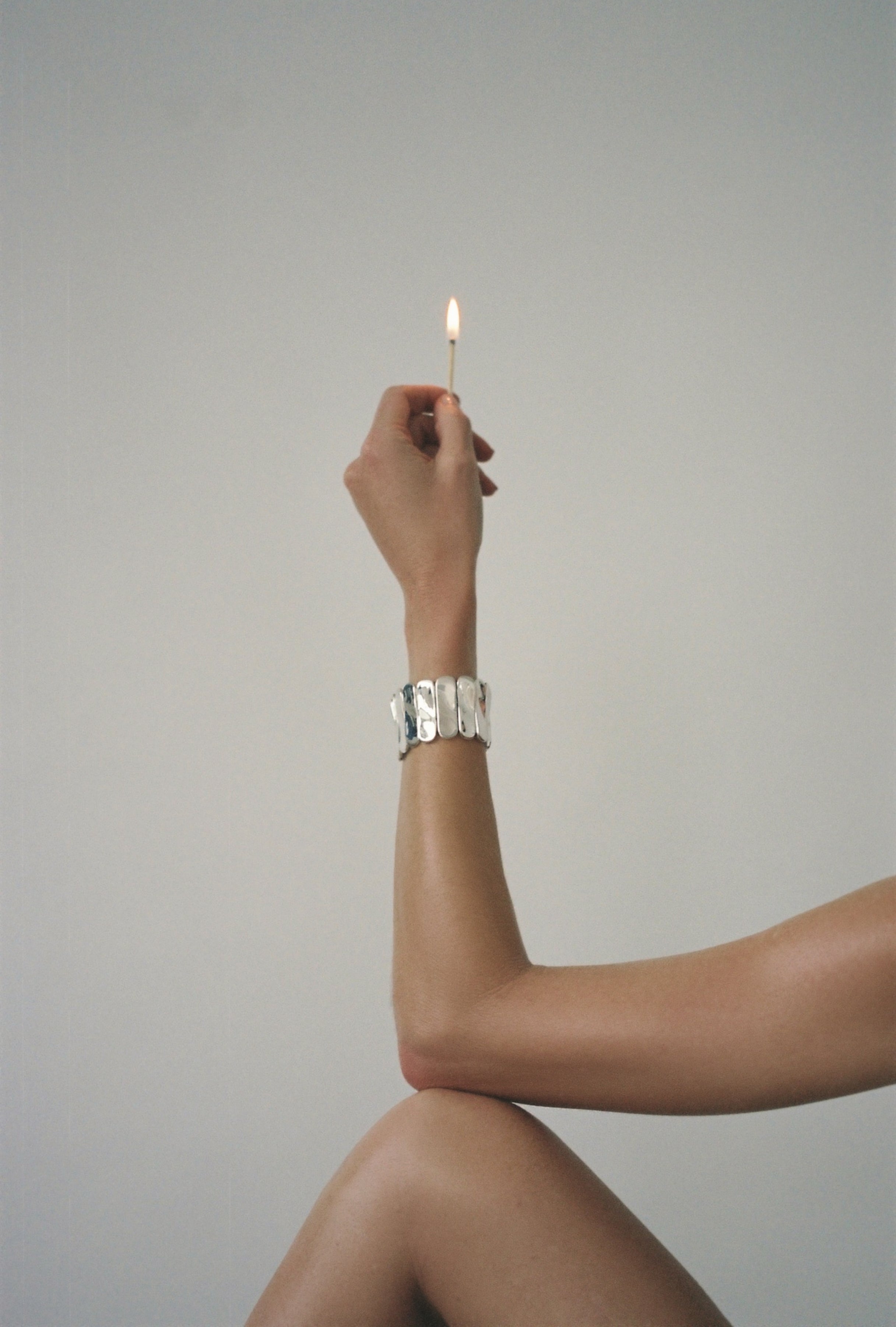 Person wearing AGMES 0.925 sterling silver Ilona Bracelet with adjustable elastic band with match in hand.