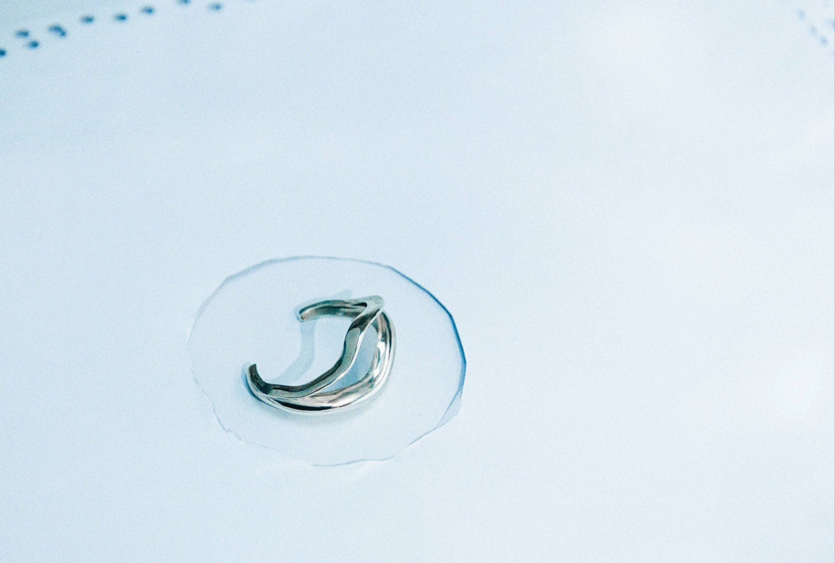 AGMES .925 sterling silver wavy sculptural Linnea cuff. On light blue background.