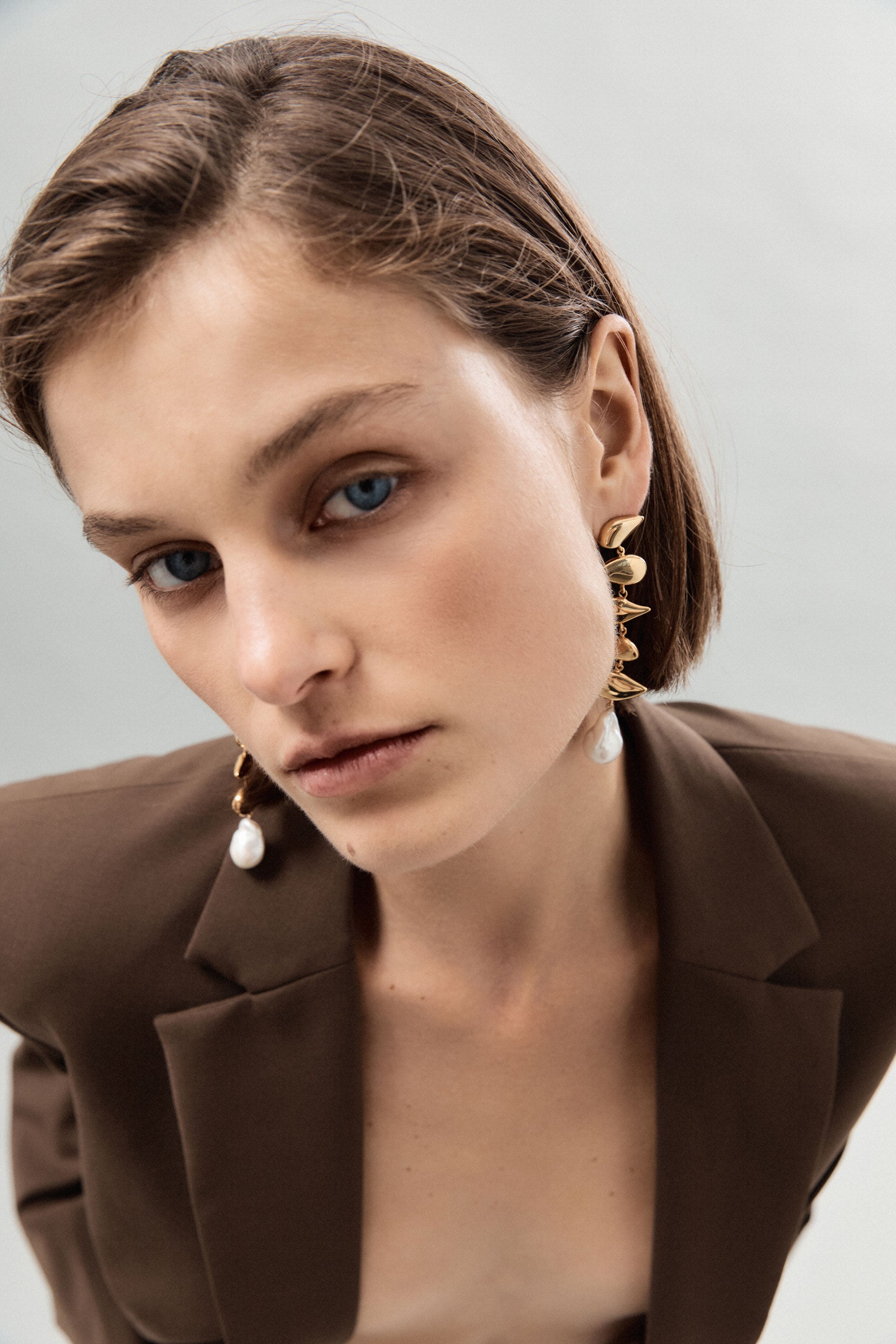 Woman wearing AGMES yellow gold vermeil long drop pearl Flora earrings.