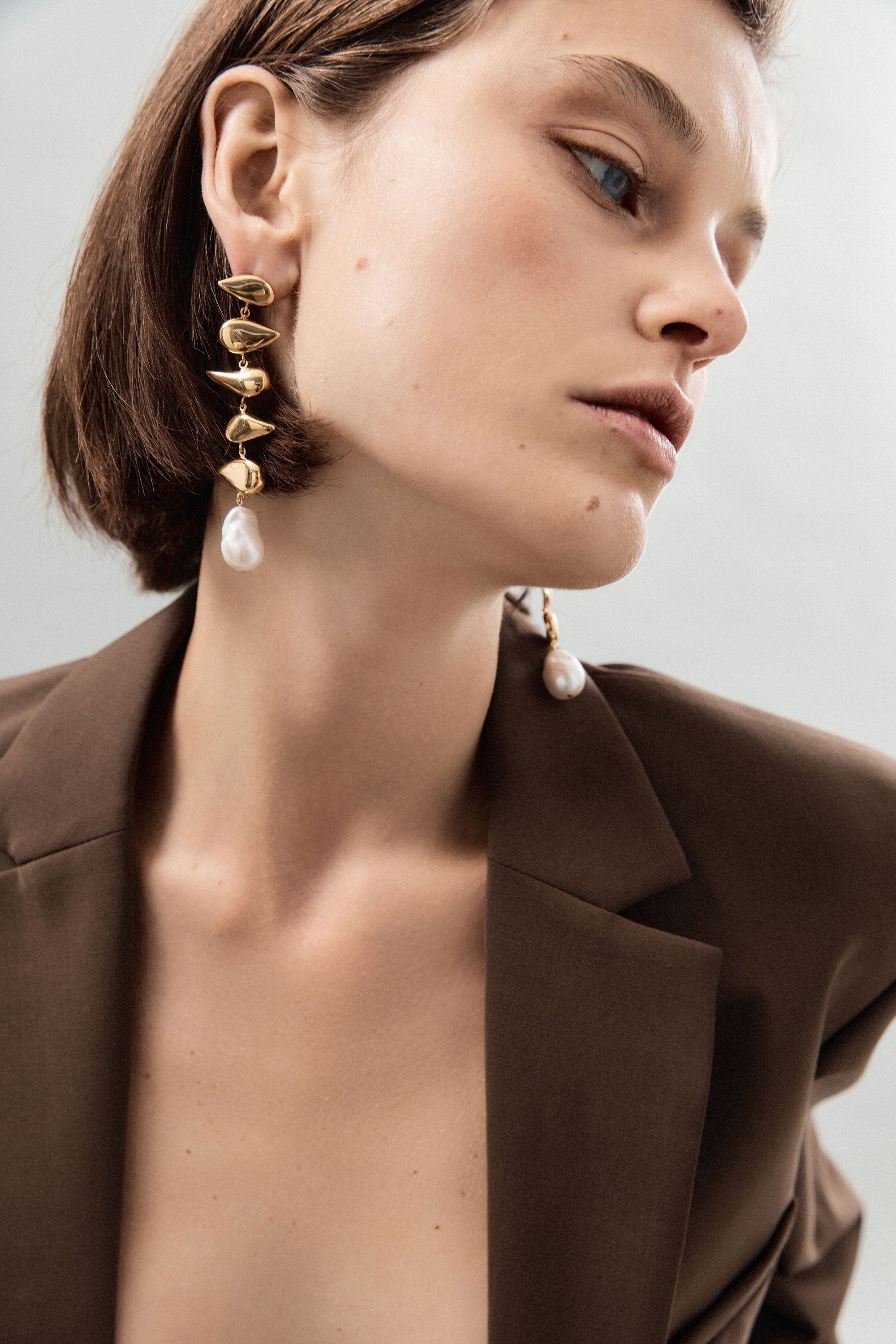 Woman wearing AGMES yellow gold vermeil long drop pearl Flora earrings.