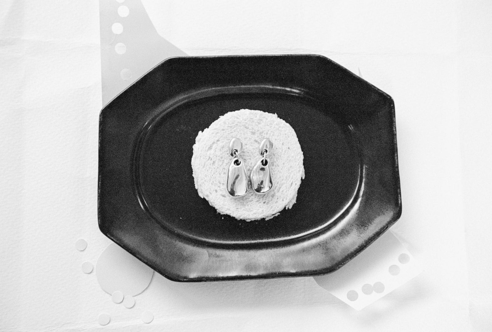 AGMES .925 sterling silver sculptural drop Luna Earrings on black plate. Black and white image.