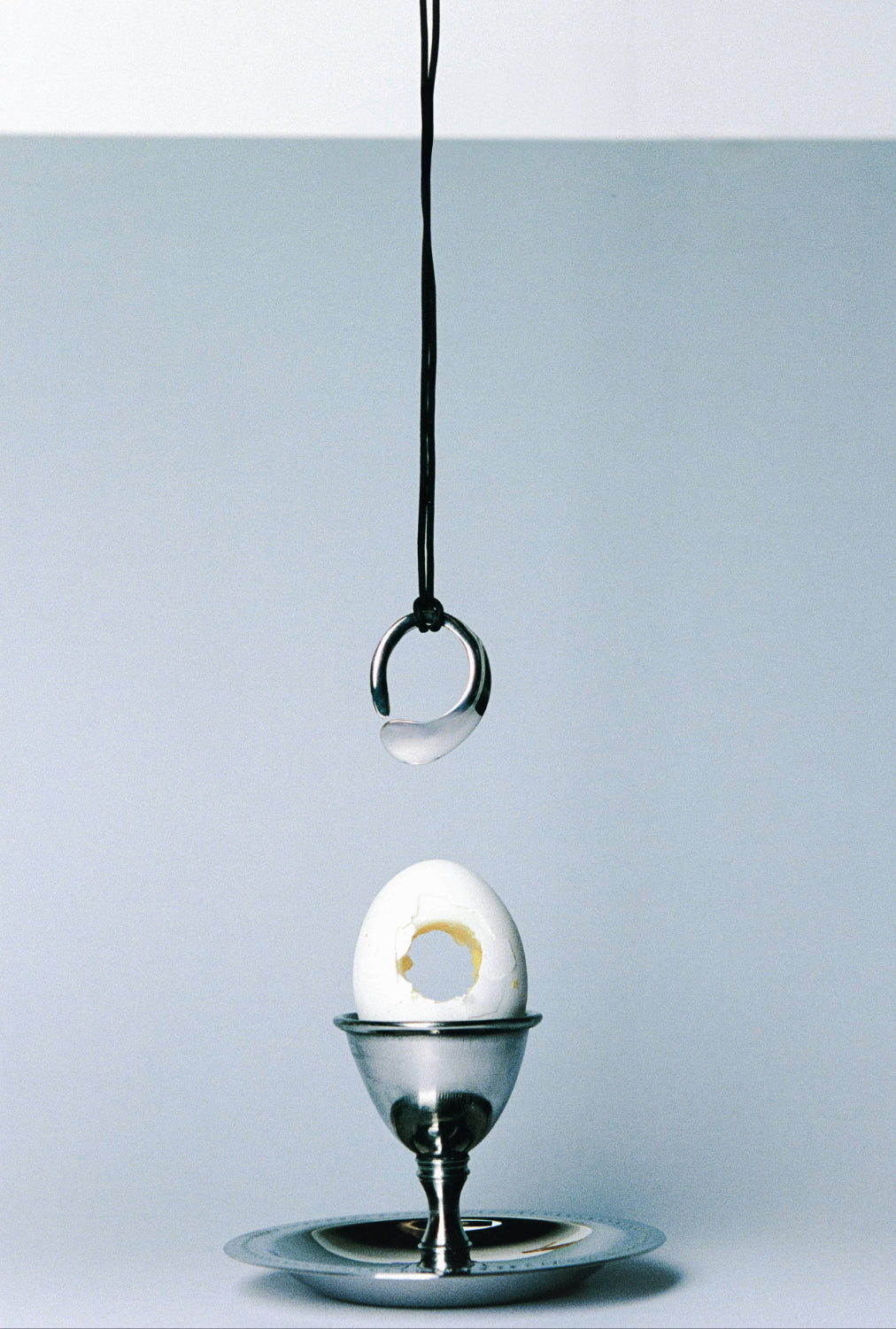 AGMES .925 sterling silver round sculptural open Marta Pedant on black suede cord. Hanging over Egg on silver holder.