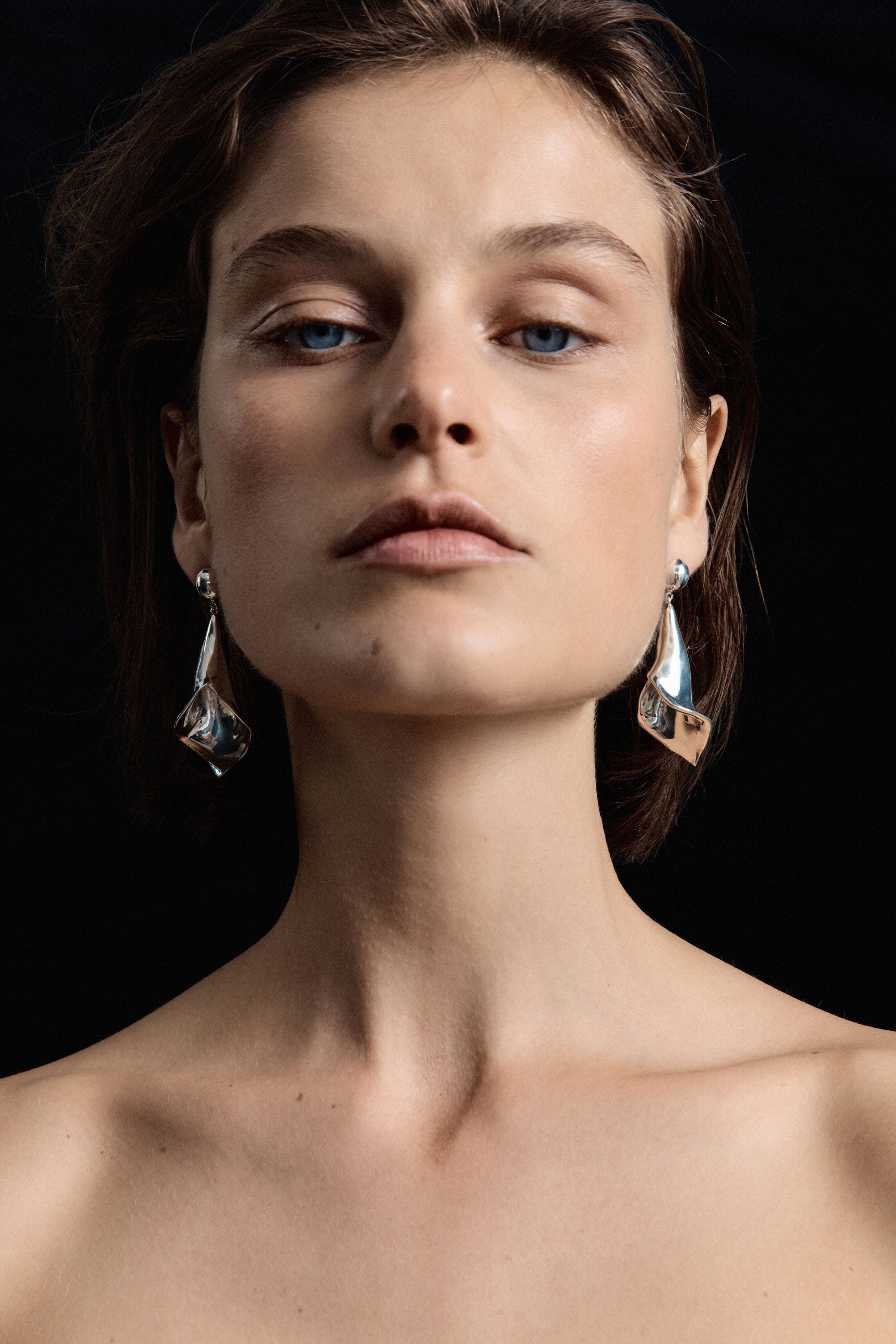 Model wearing AGMES .925 sterling silver Medium Calla drop Earrings. Black background.
